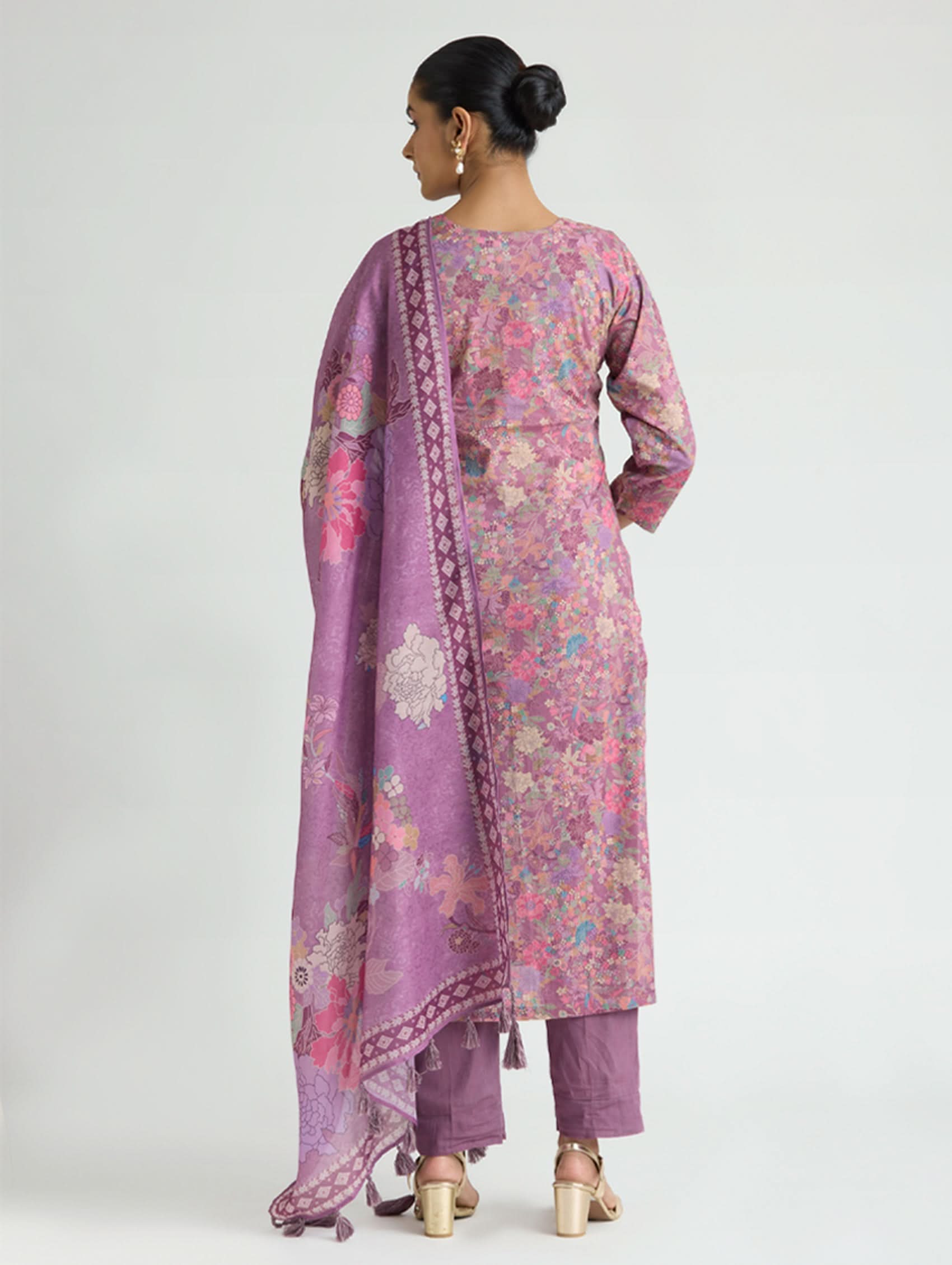Woman wearing a pink and purple floral traditional outfit on a white background