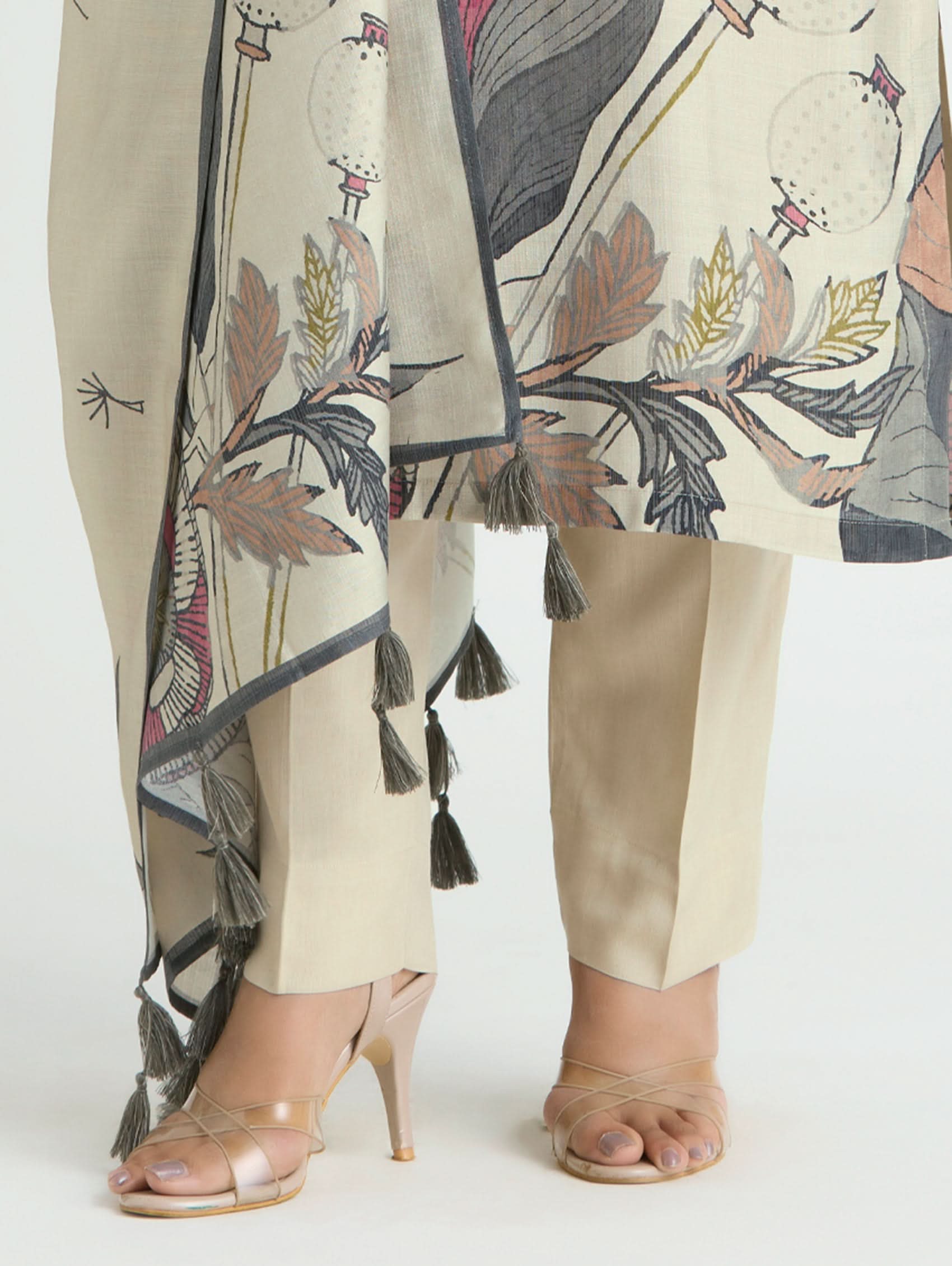 Beige outfit with floral patterns and tassels on a white background