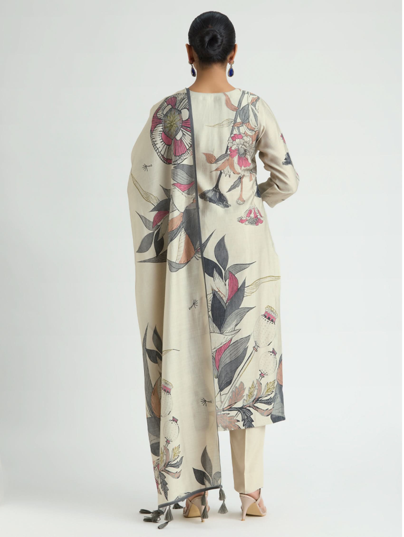 Woman wearing a long, light-colored dress with floral patterns on a white background