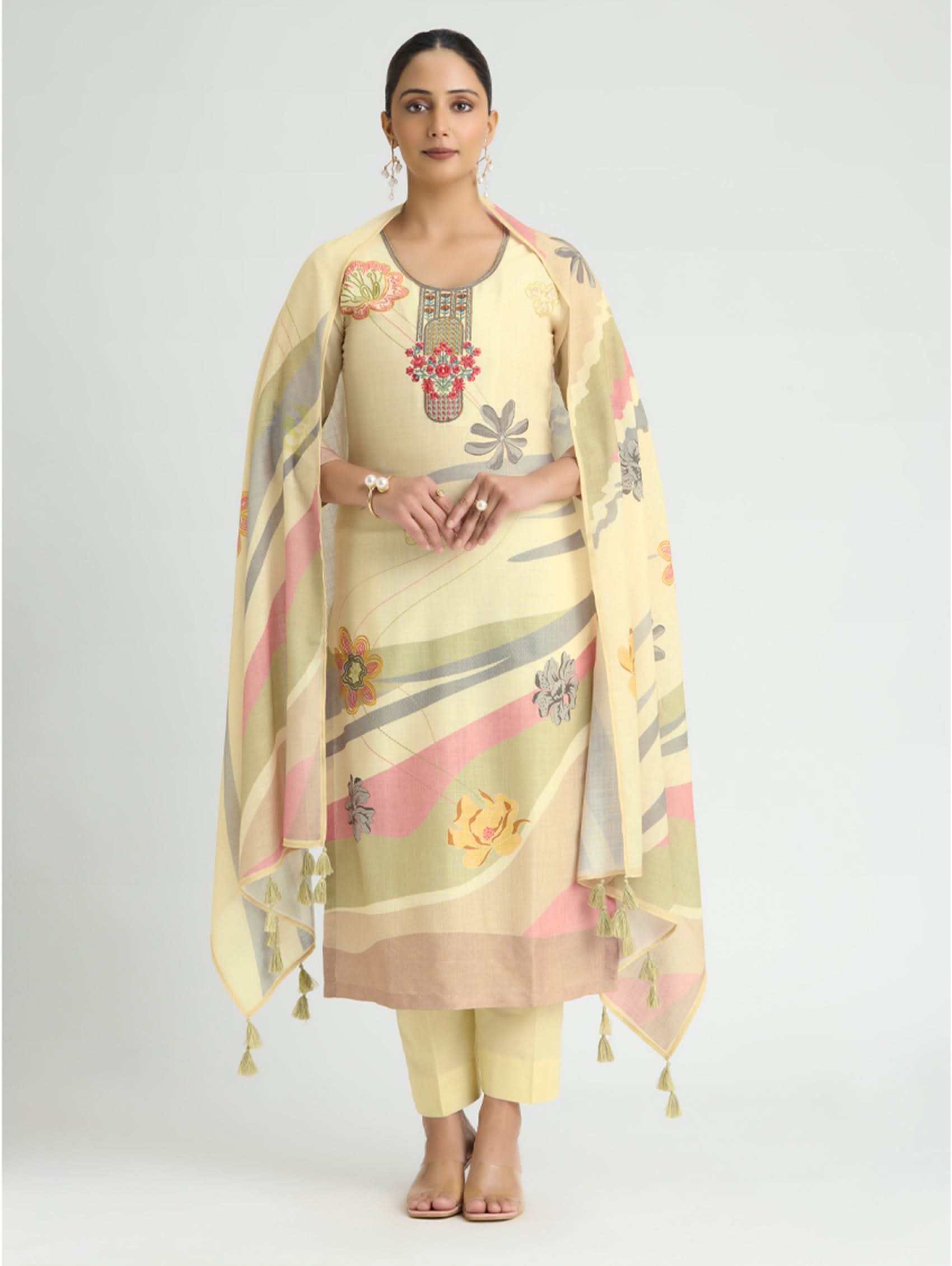 Woman wearing a light yellow traditional outfit with floral patterns on a plain background