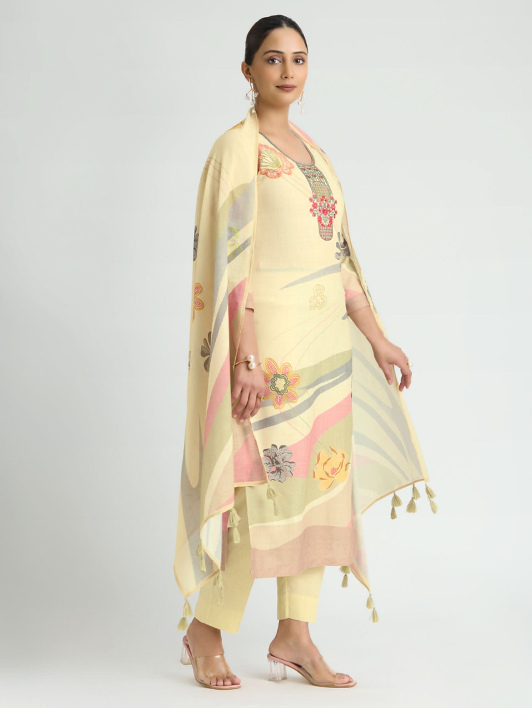 Woman wearing a light yellow floral dress with a matching dupatta on a white background