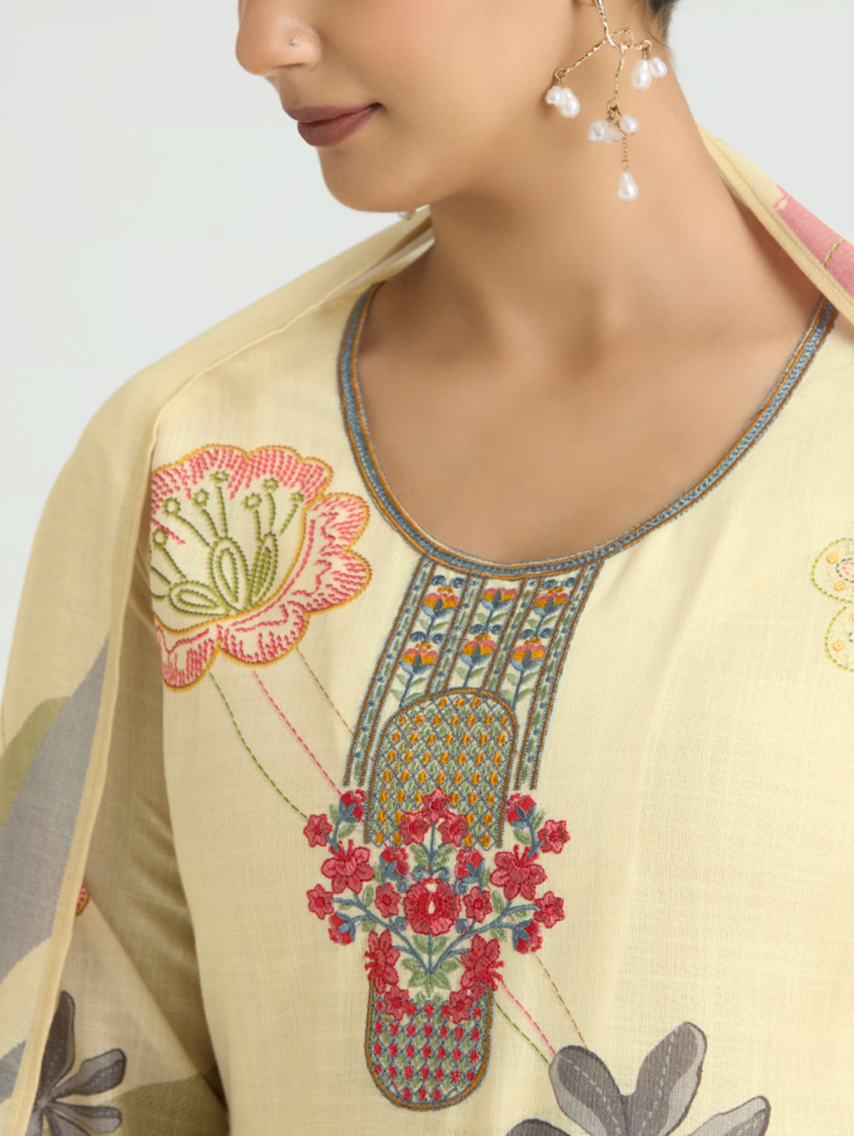 Beige embroidered garment with floral patterns on a plain background