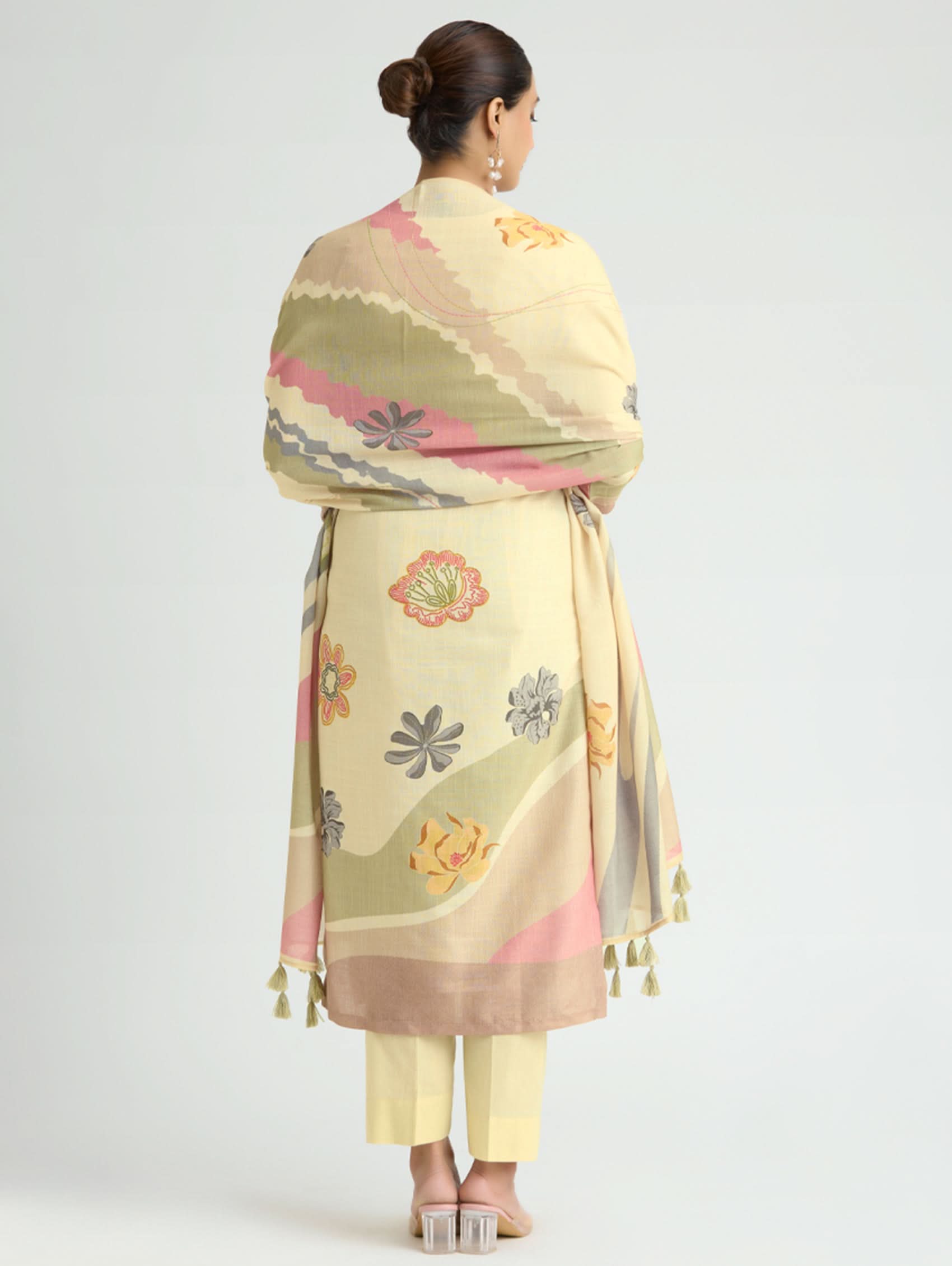 Woman wearing a patterned shawl with floral designs on a plain background