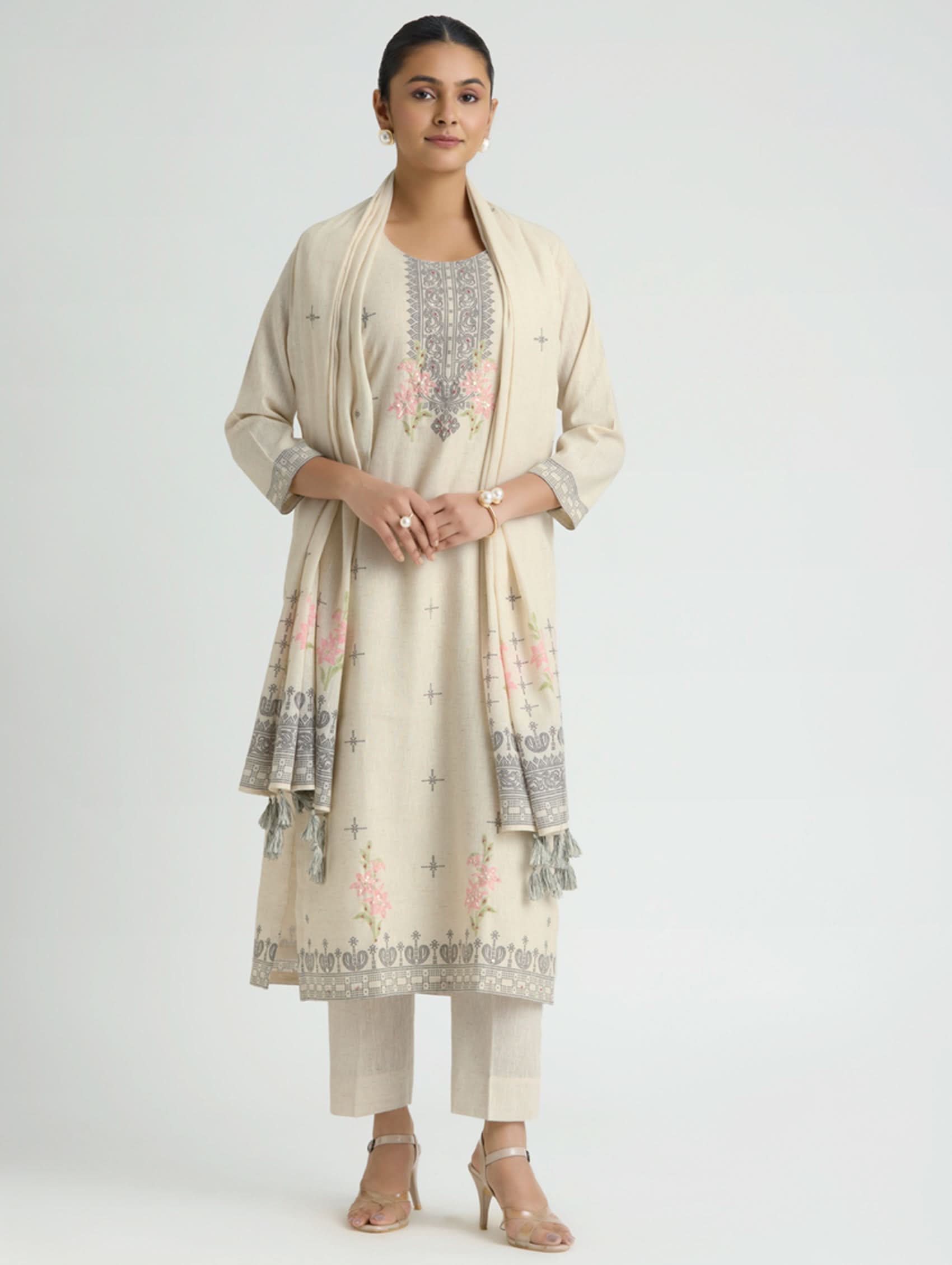 Woman wearing a cream-colored traditional outfit with floral patterns on a white background