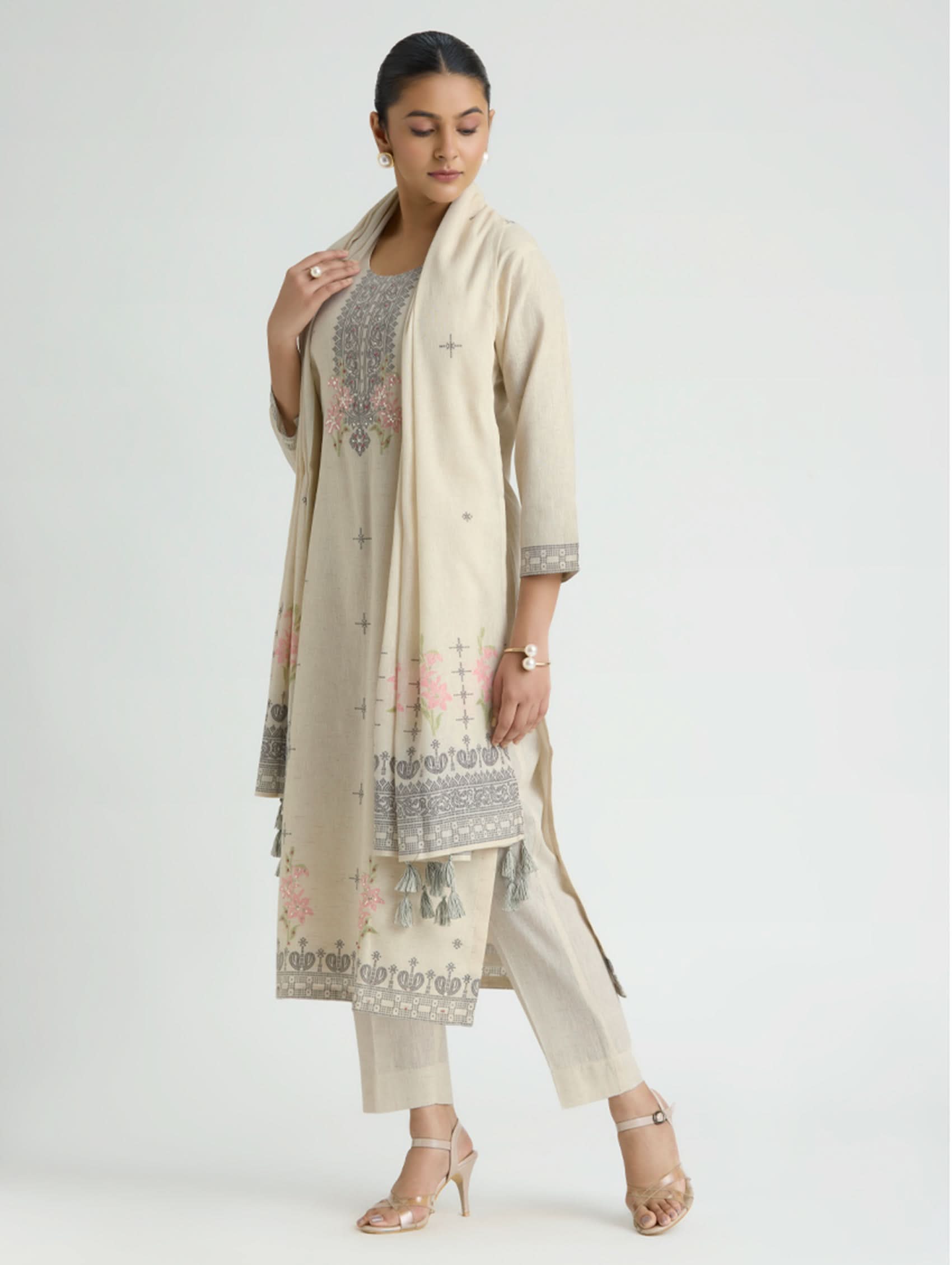 Woman wearing a beige traditional outfit with a matching dupatta on a white background