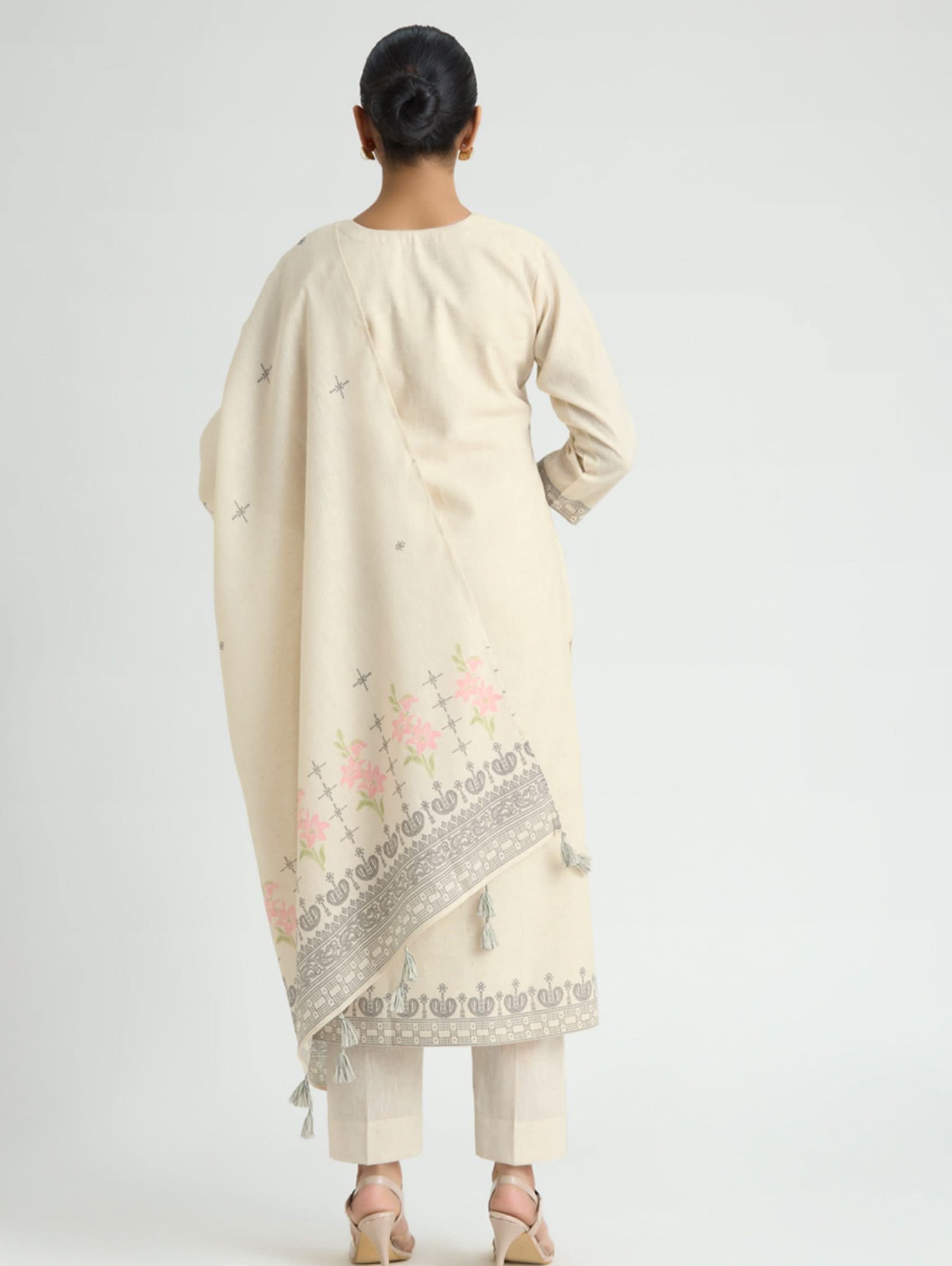 Woman wearing a cream-colored traditional outfit with floral embroidery on a white background