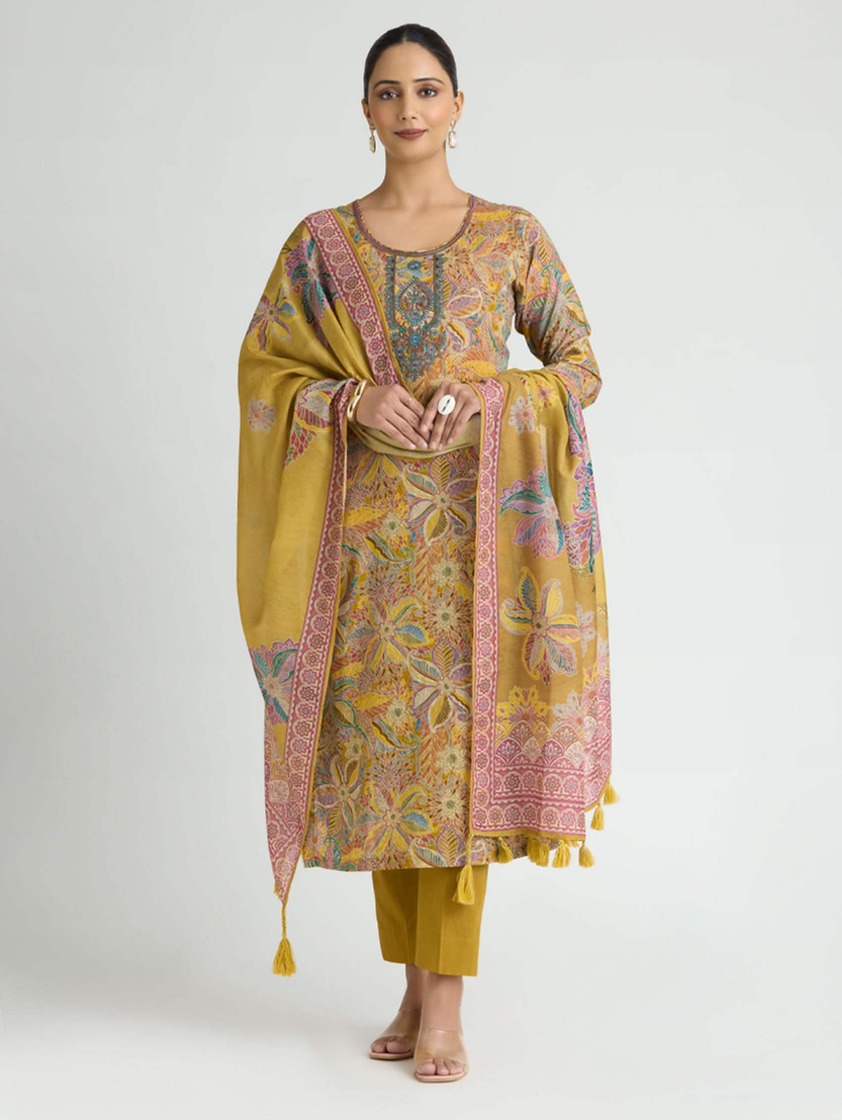 Woman wearing a mustard yellow traditional outfit with a patterned duppata on a white background