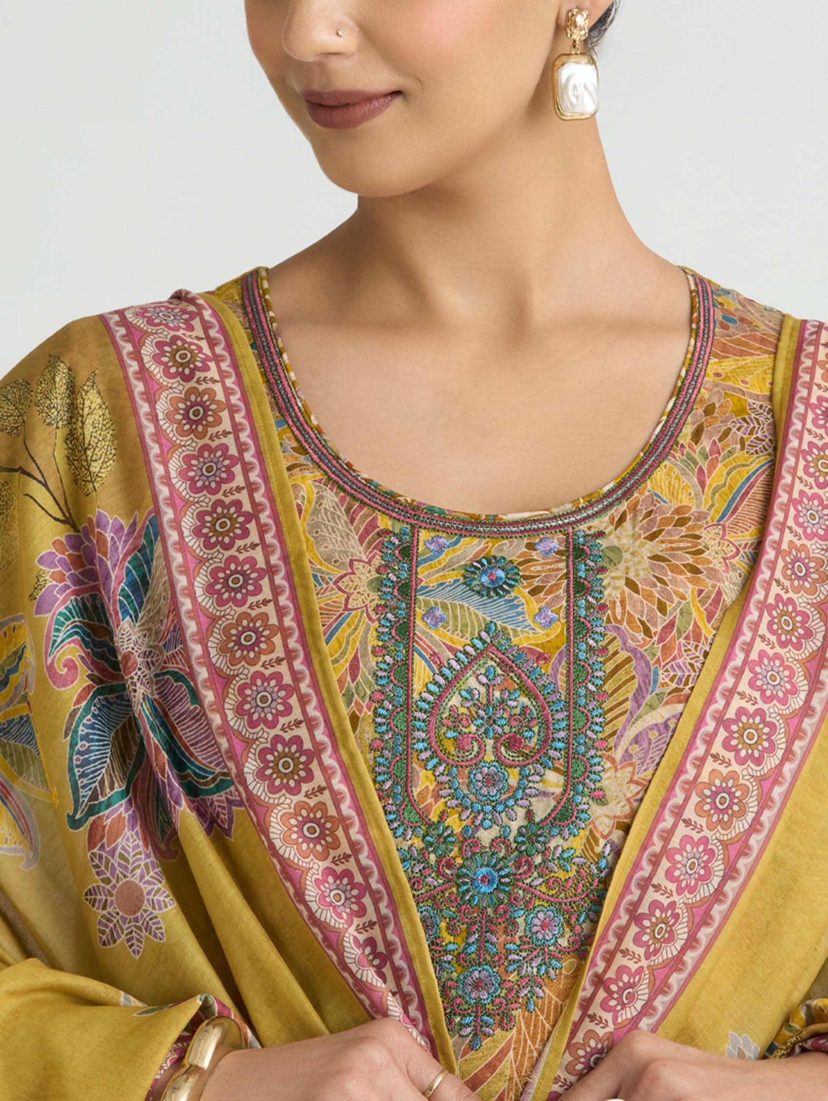 Close-up of a person wearing a patterned yellow garment with intricate designs.