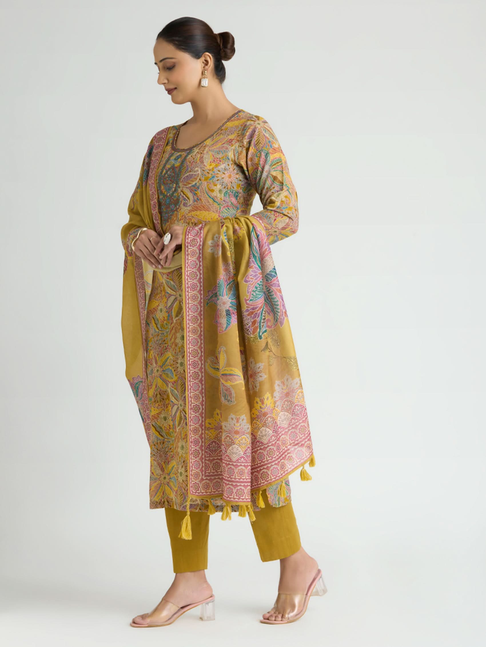 Woman wearing a patterned yellow kurta with matching pants on a white background