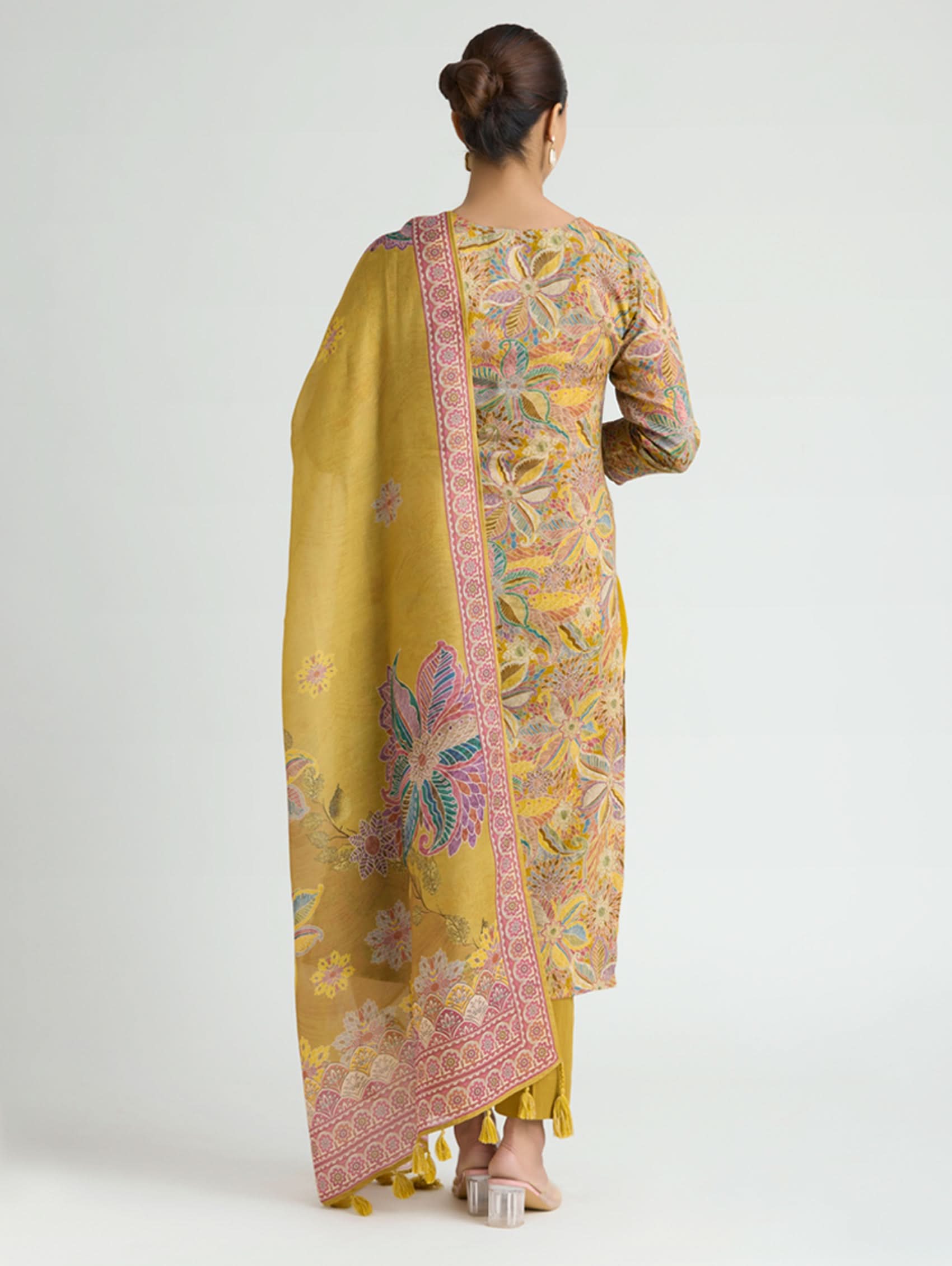 Woman wearing a yellow floral dress with a matching dupatta on a white background