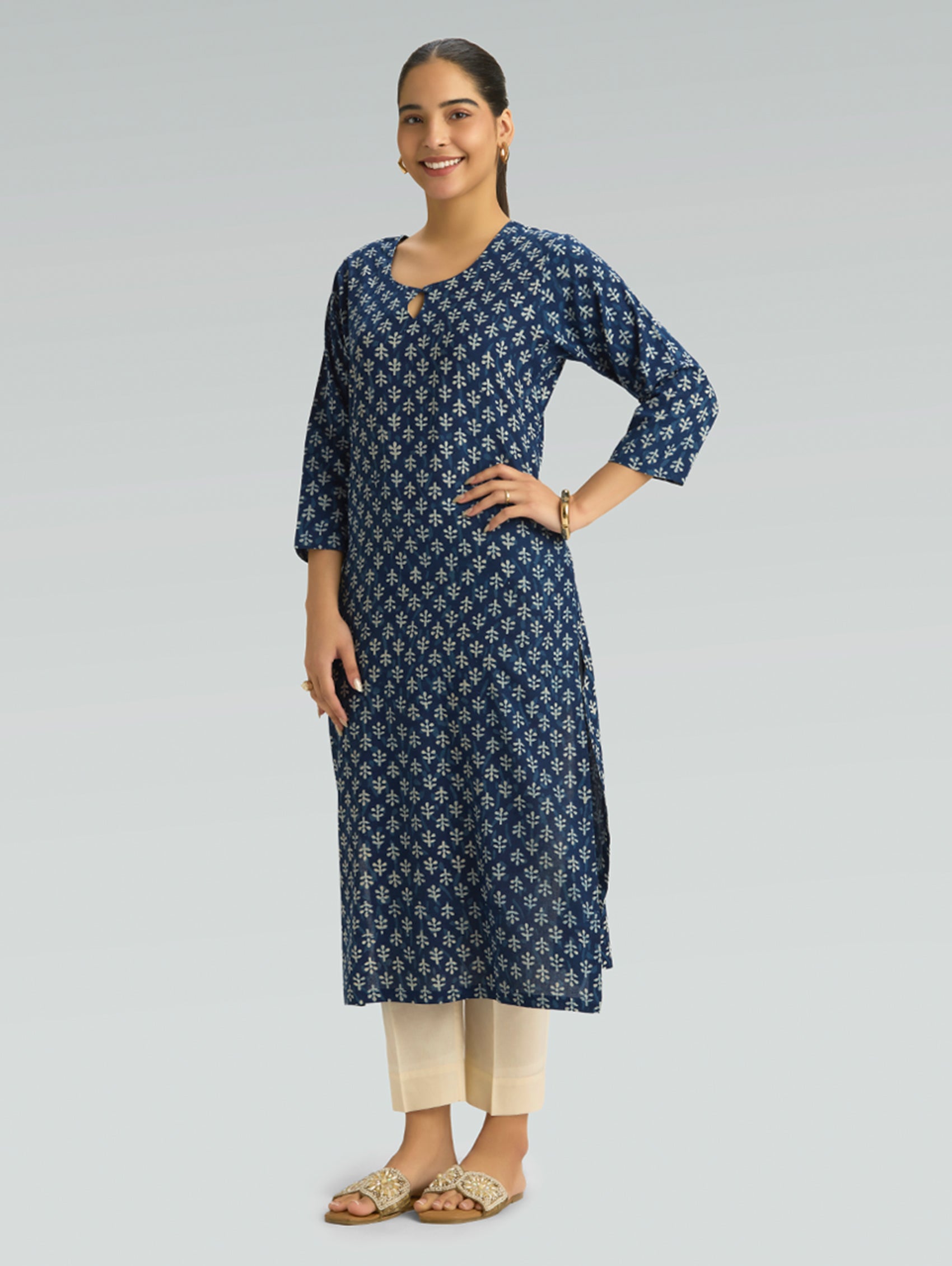 Woman wearing a navy blue patterned kurta with beige pants on a gray background