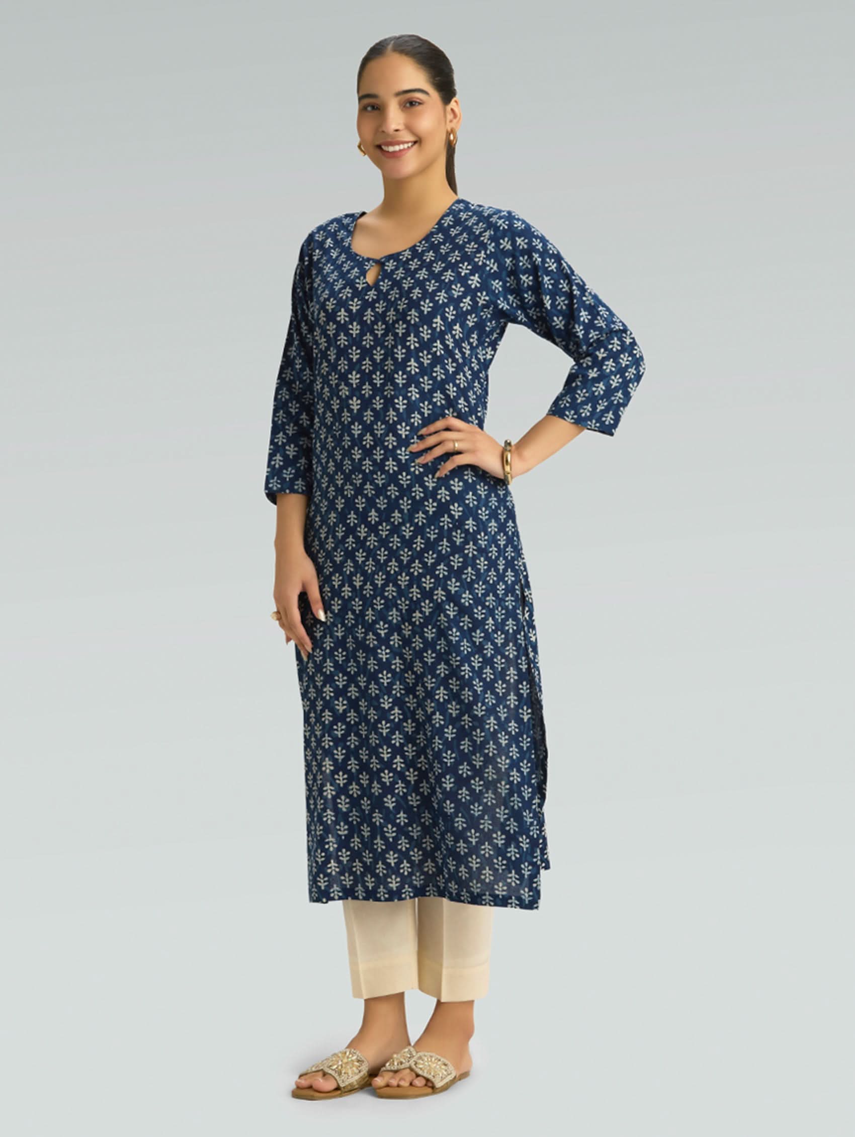 Woman wearing a navy blue patterned kurta with beige pants on a gray background