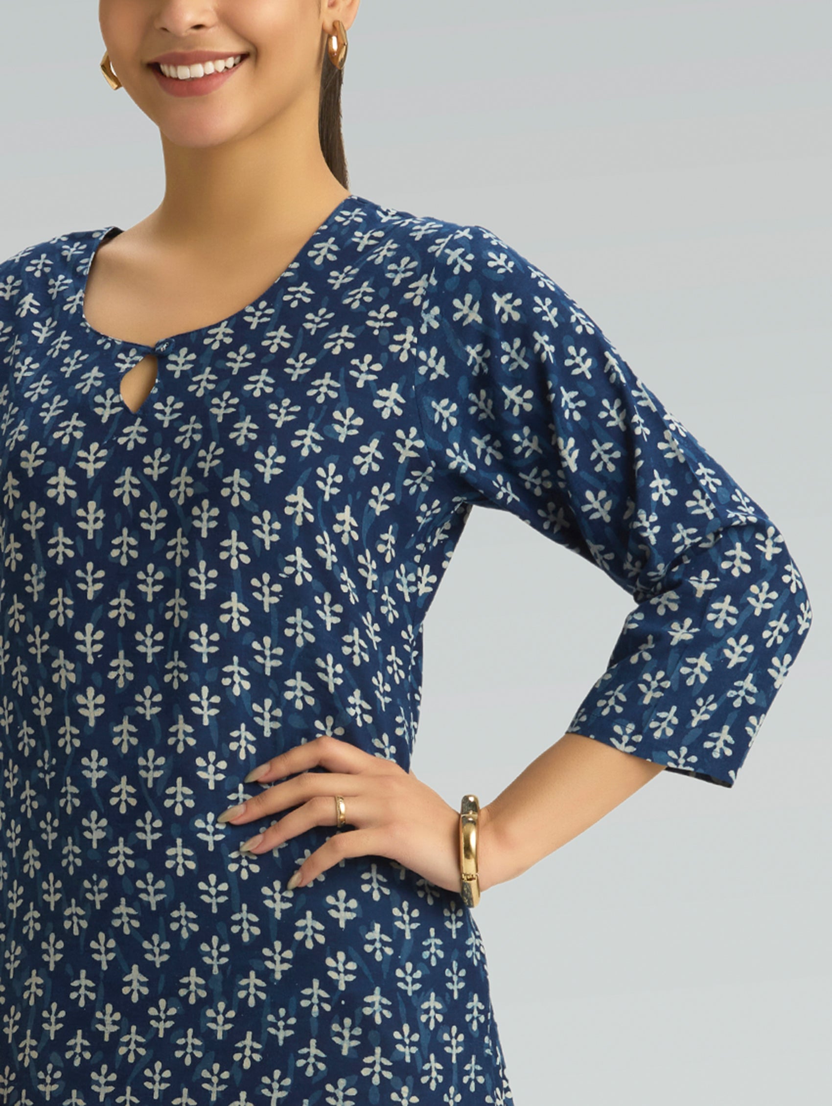 Woman wearing a blue patterned dress against a gray background