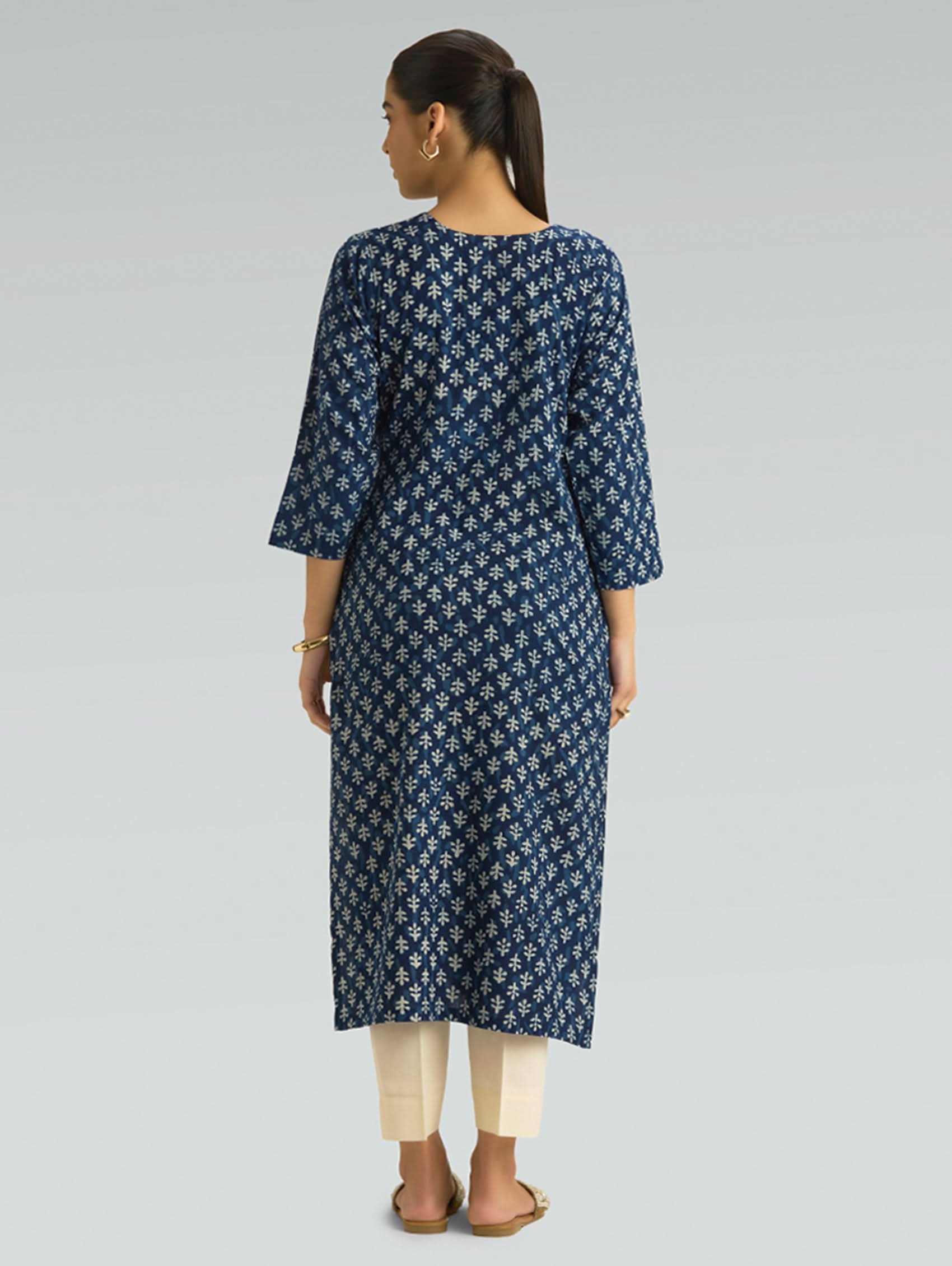 Woman wearing a blue patterned kurta with beige pants on a light gray background