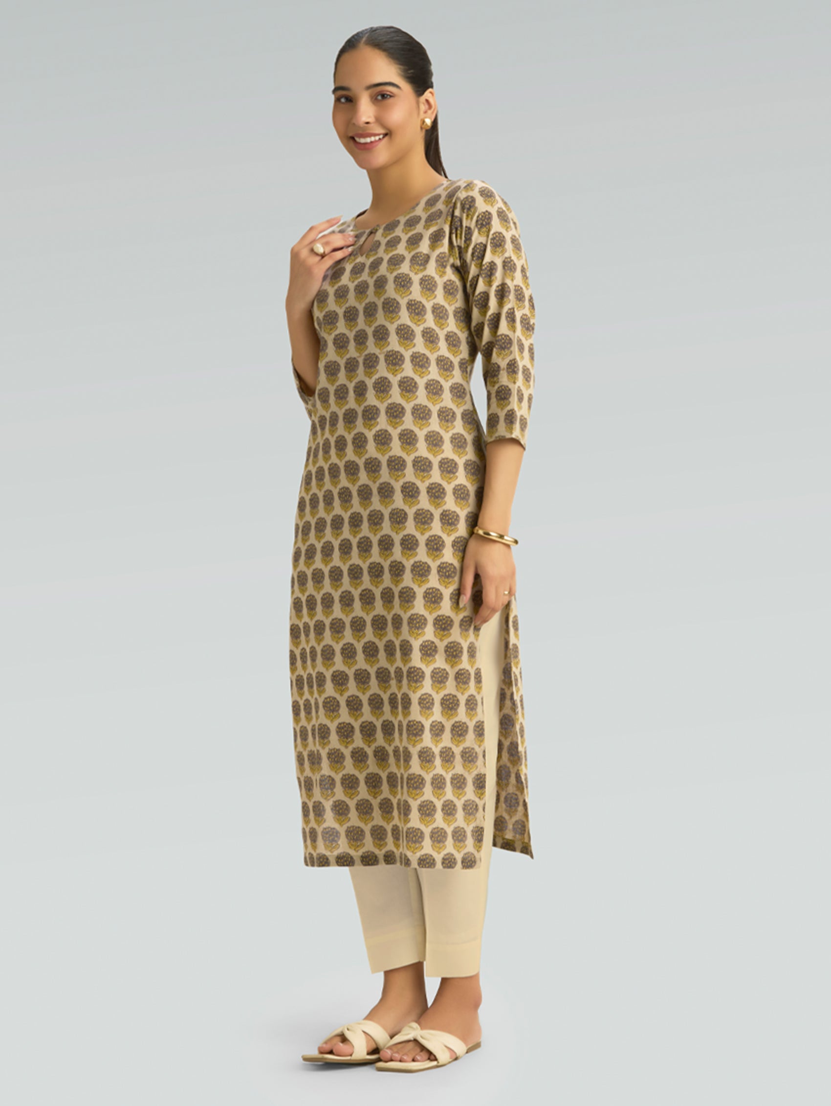 Woman wearing a patterned kurta with beige pants on a gray background