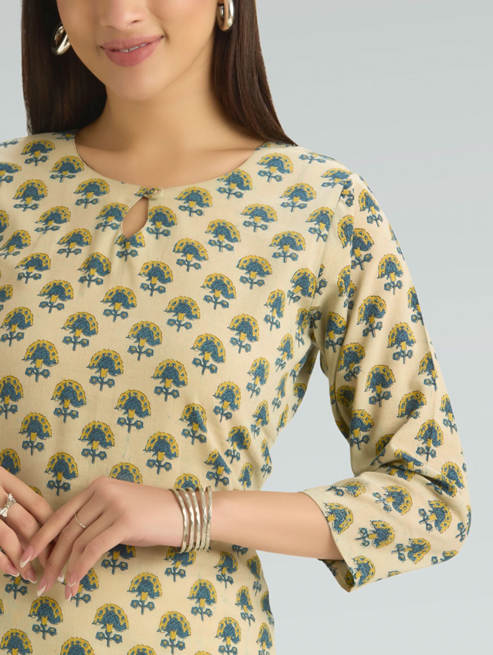 Woman wearing a beige dress with blue floral pattern on a gray background