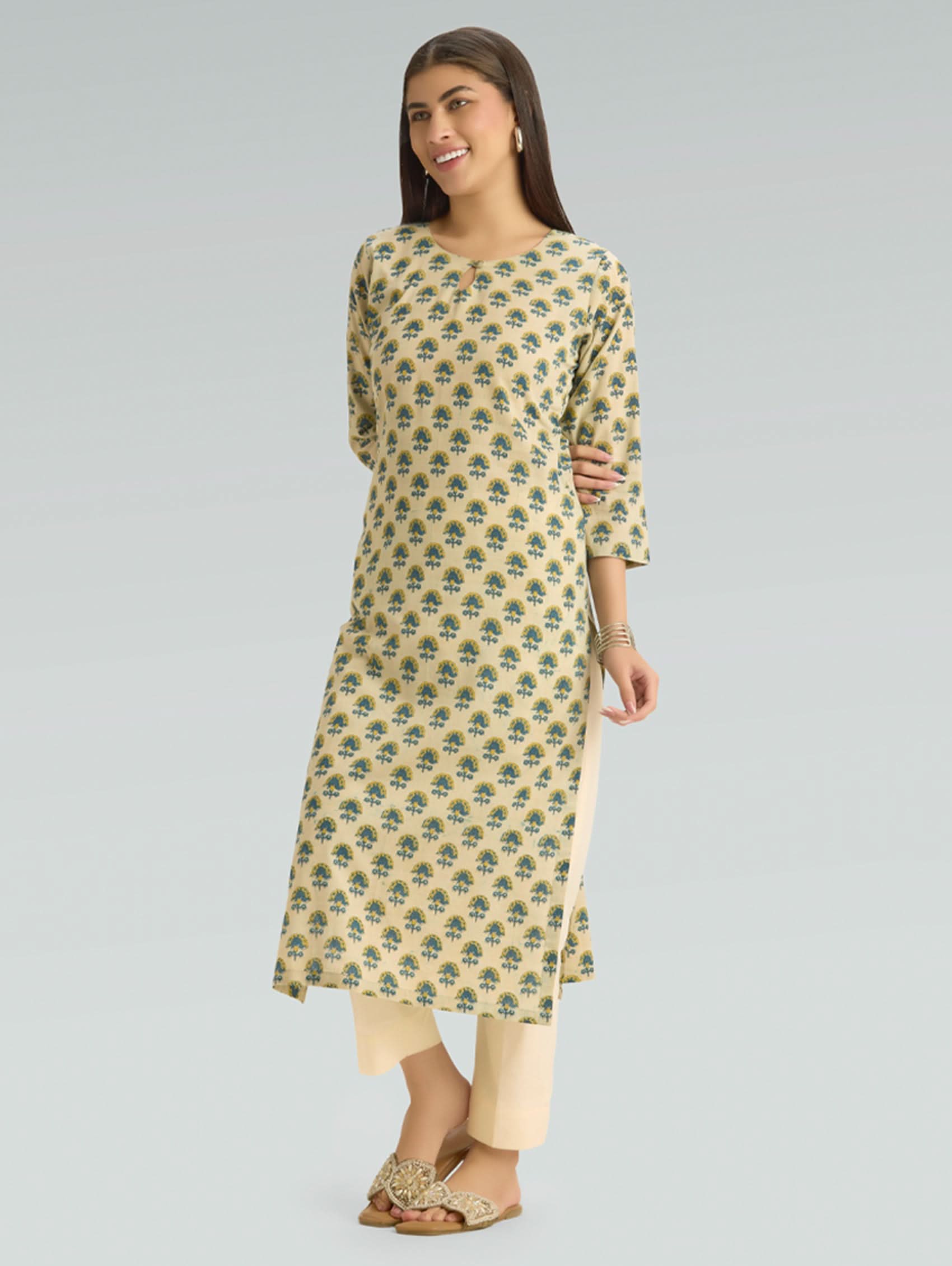 Woman wearing a patterned kurta with beige pants on a gray background