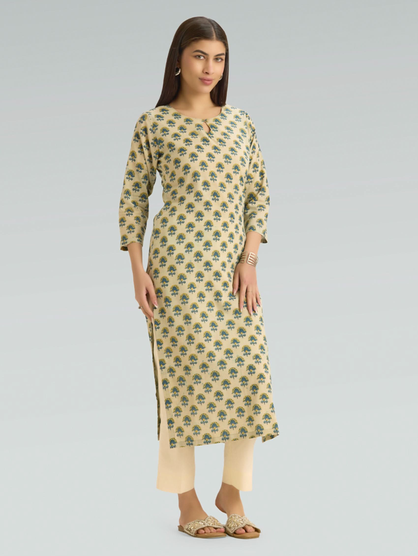 Woman wearing a patterned kurta with beige pants on a gray background