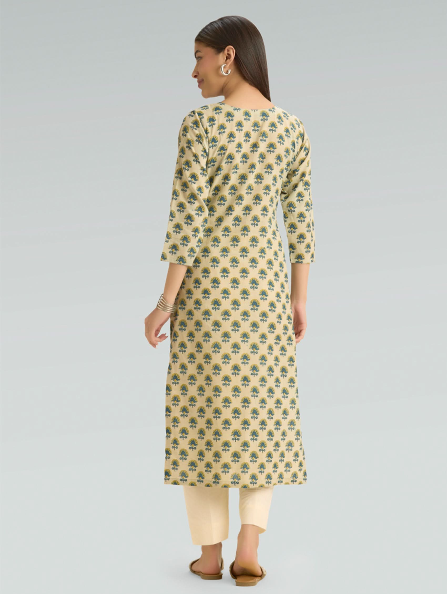 Woman wearing a patterned kurta with beige pants on a gray background