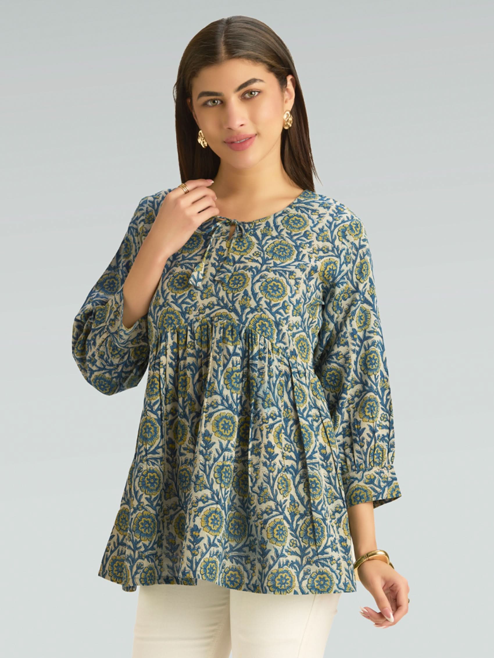 Woman wearing a patterned blue and green top against a gray background