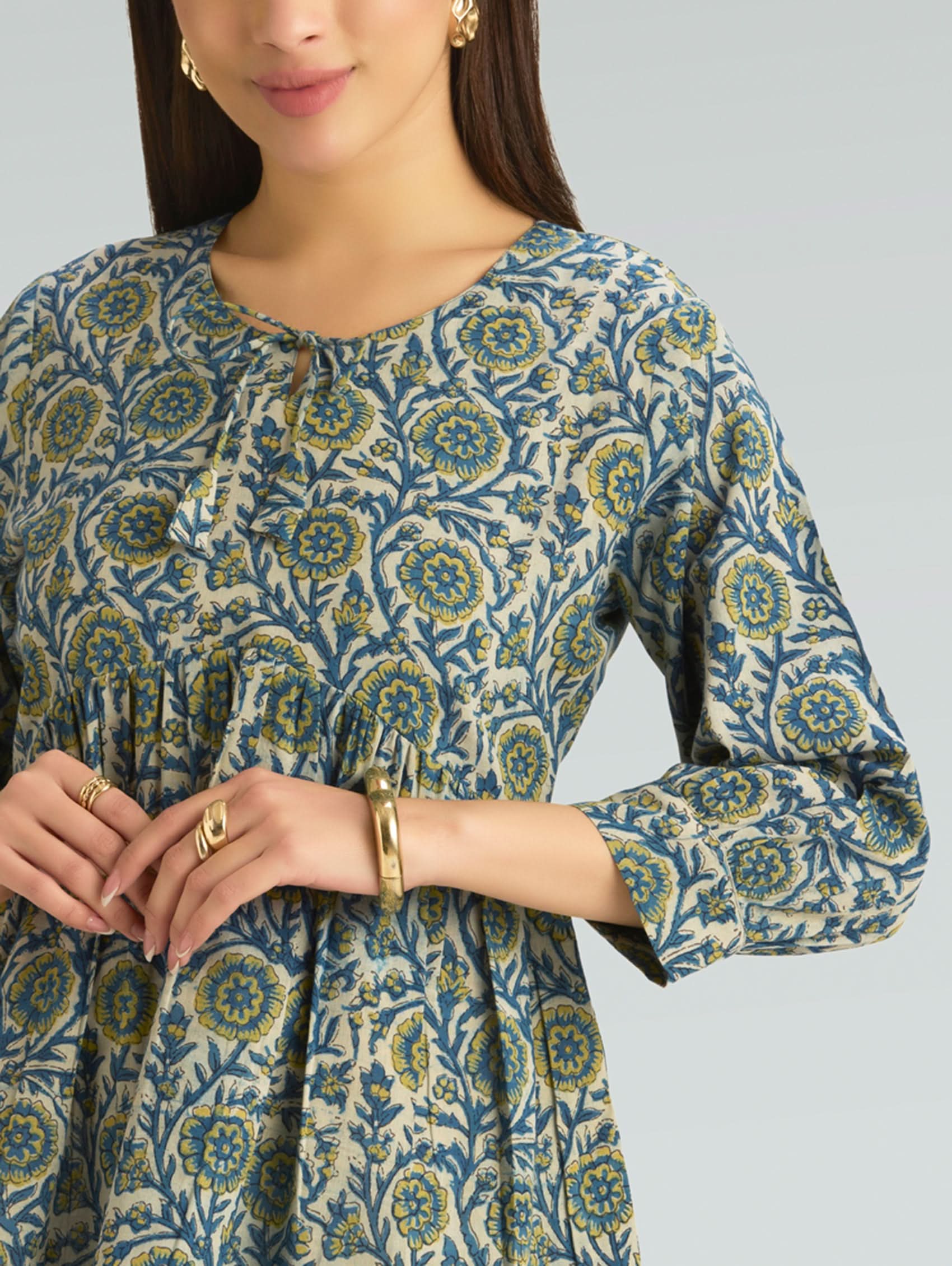 Woman wearing a patterned dress with long sleeves on a gray background
