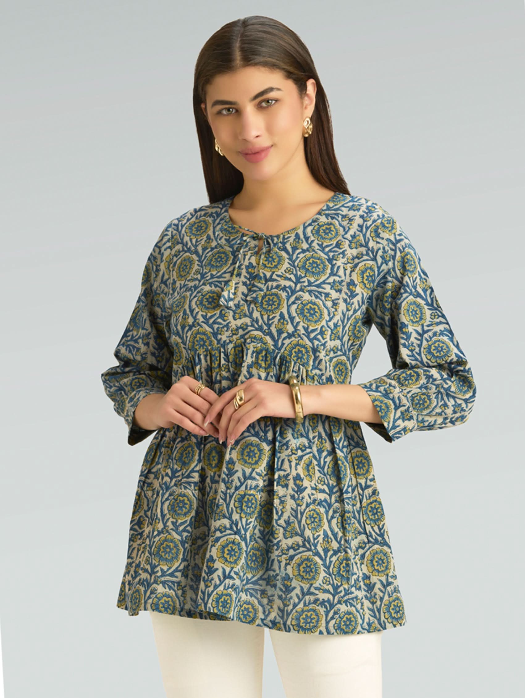 Woman wearing a green and blue patterned top on a gray background