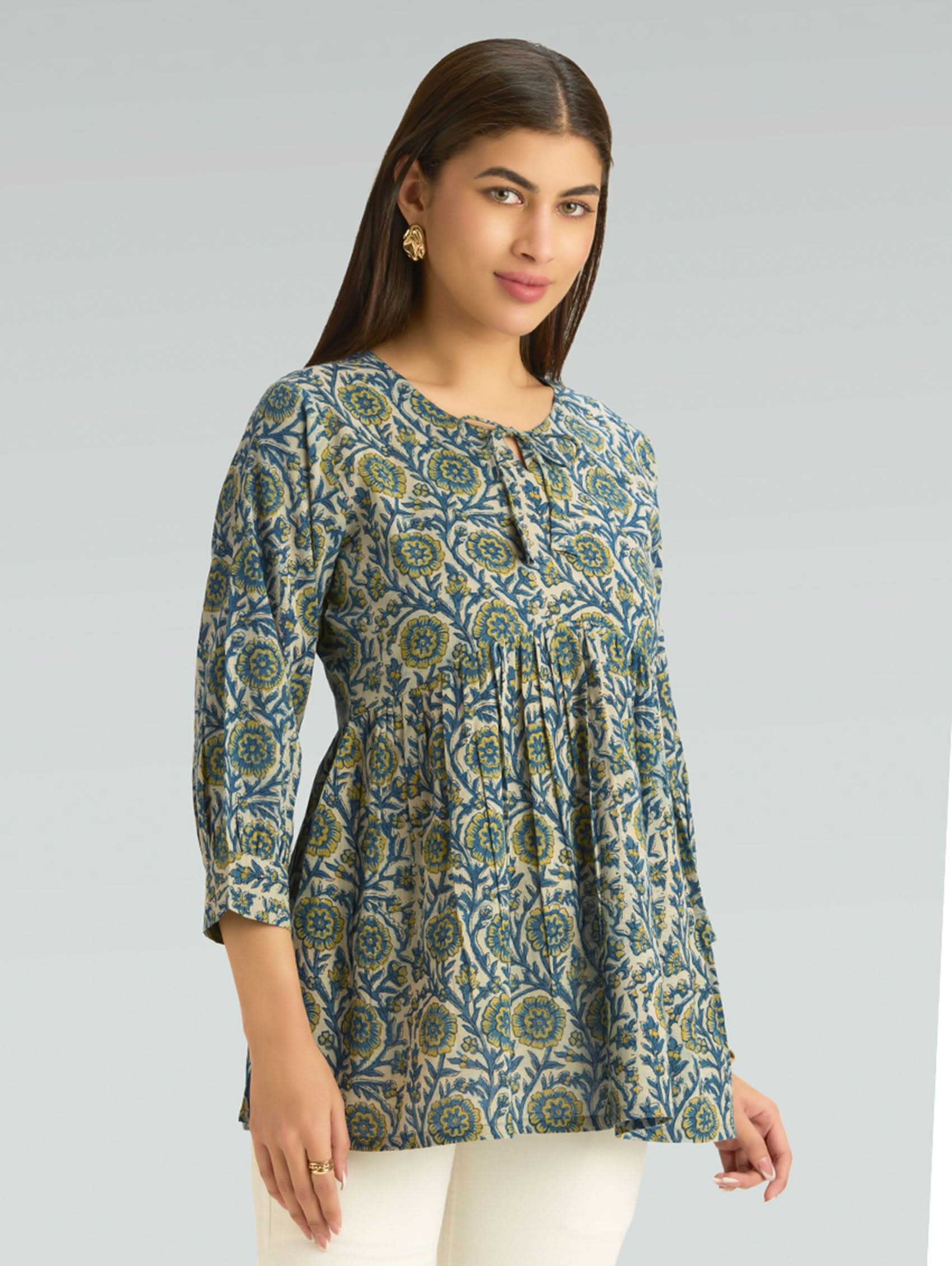 Woman wearing a patterned long-sleeve top on a gray background