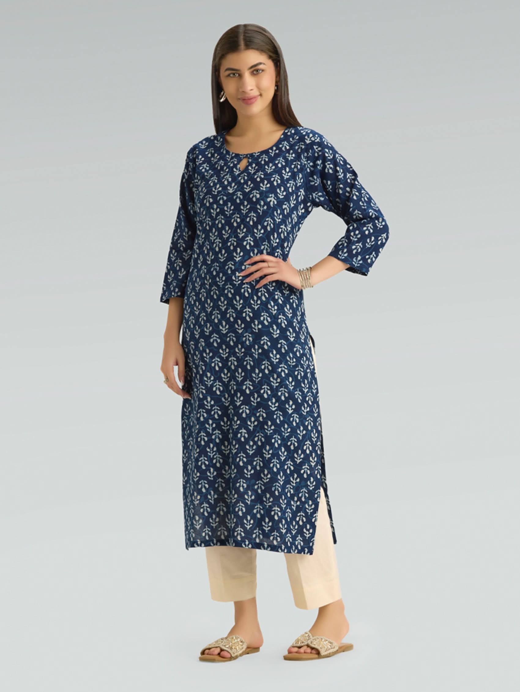 Woman wearing a blue patterned kurta with beige pants on a gray background