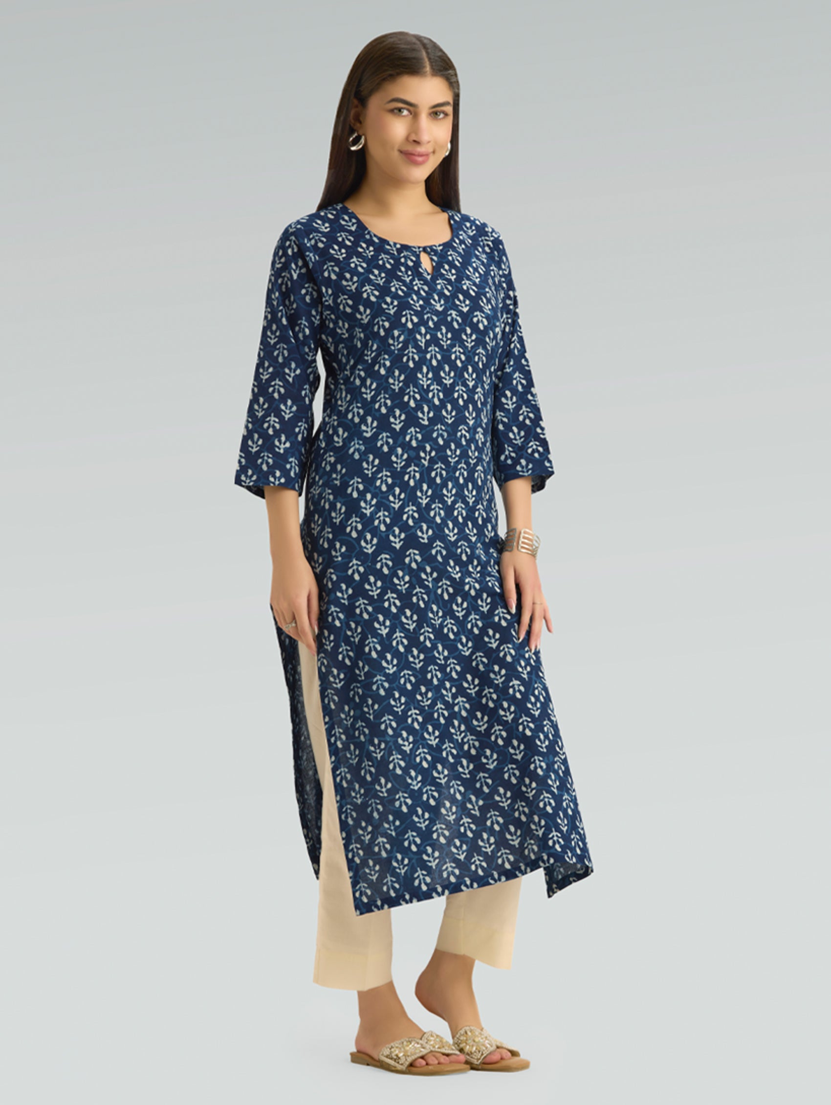 Woman wearing a blue patterned kurta with beige pants on a gray background
