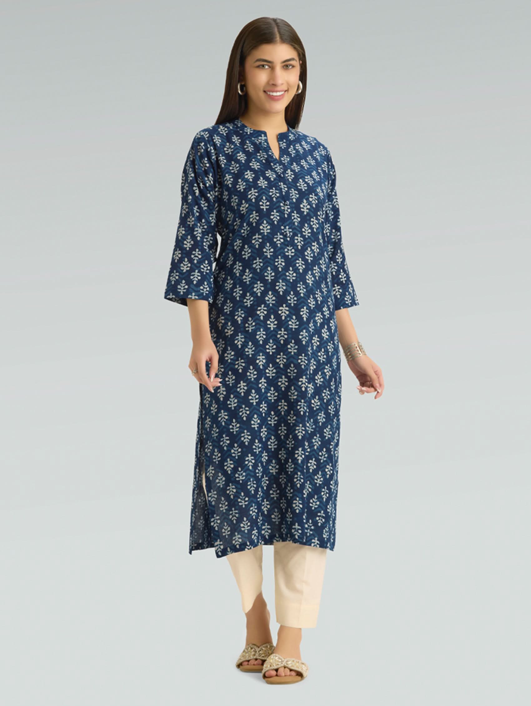 Woman wearing a blue floral patterned kurta with beige pants on a gray background