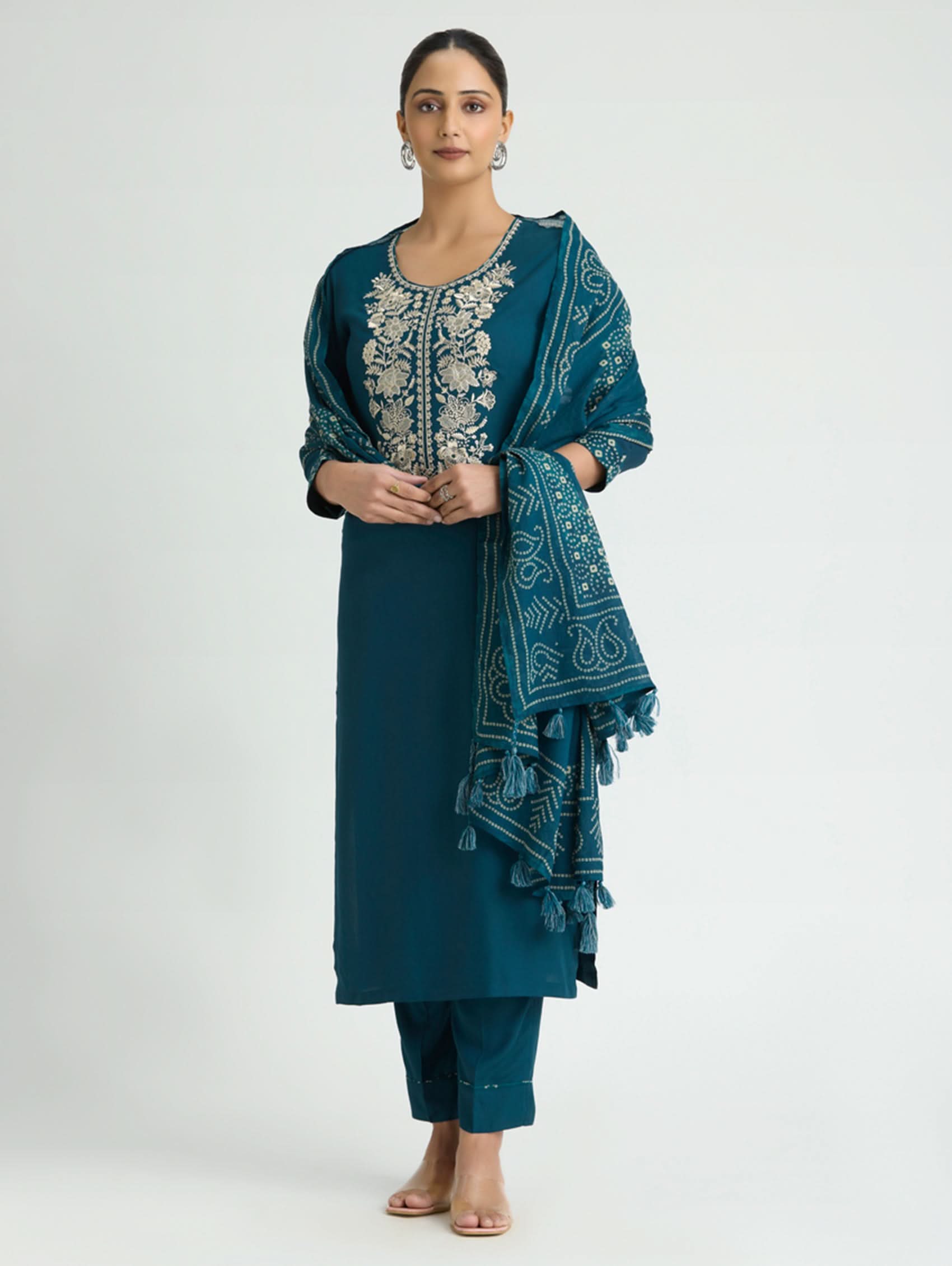 Woman wearing a teal traditional outfit with a matching dupatta on a white background