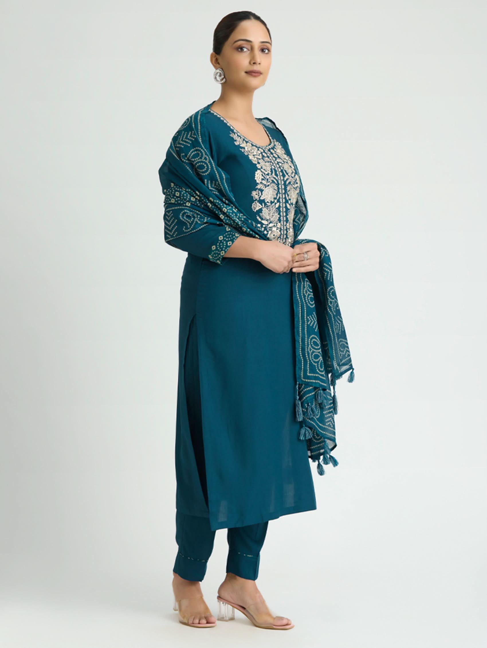 Woman wearing a teal outfit with a matching shawl on a white background