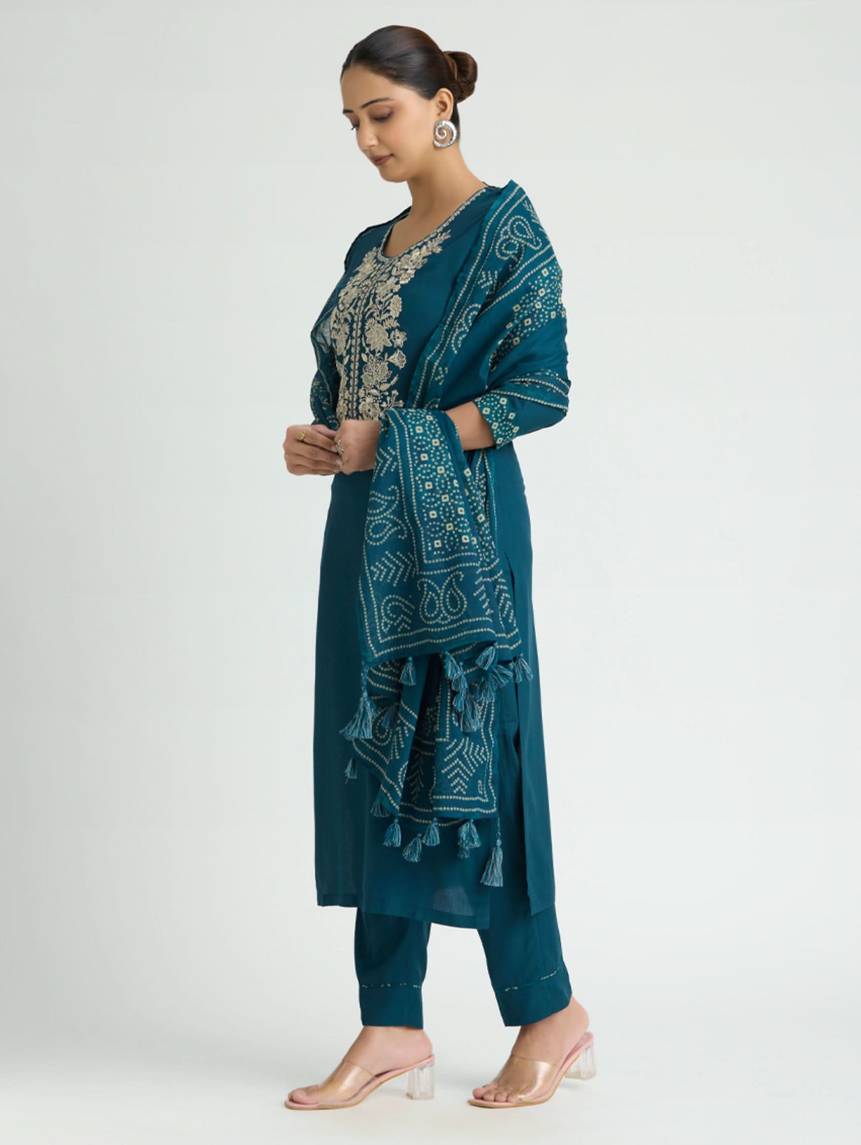 Woman wearing a teal embroidered outfit on a white background