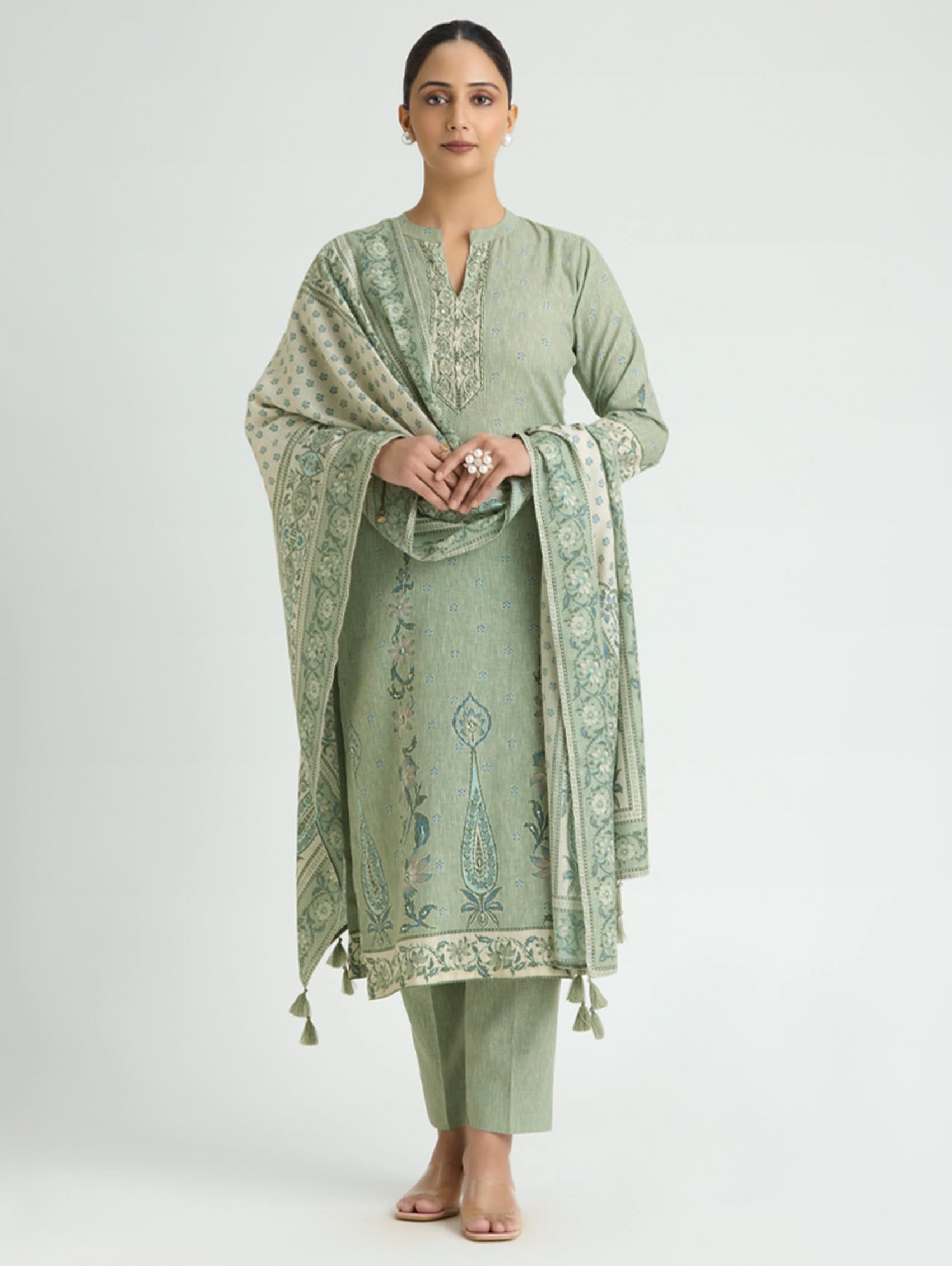 Woman wearing a light green traditional outfit with a matching dupatta on a white background