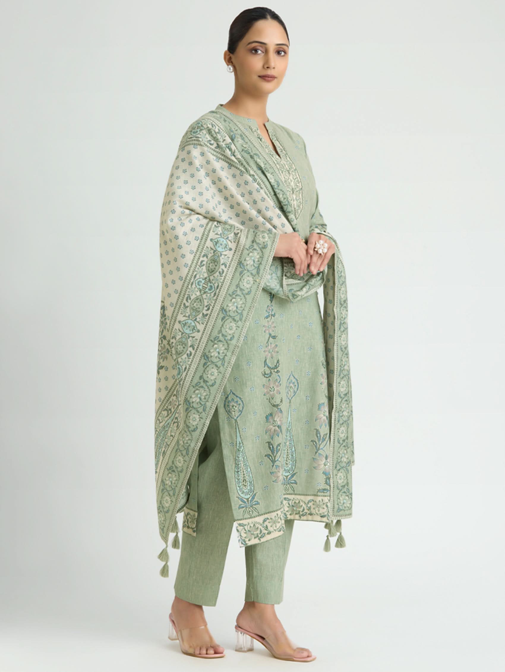 Woman wearing a light green traditional outfit with a matching dupatta on a white background