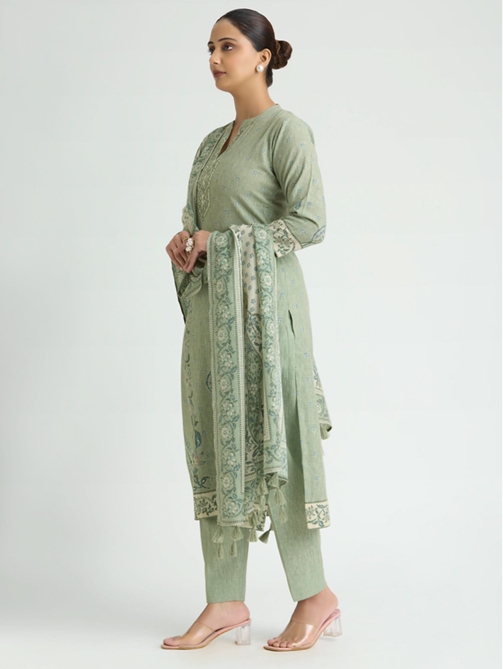 Woman wearing a green traditional outfit with a matching dupatta on a white background