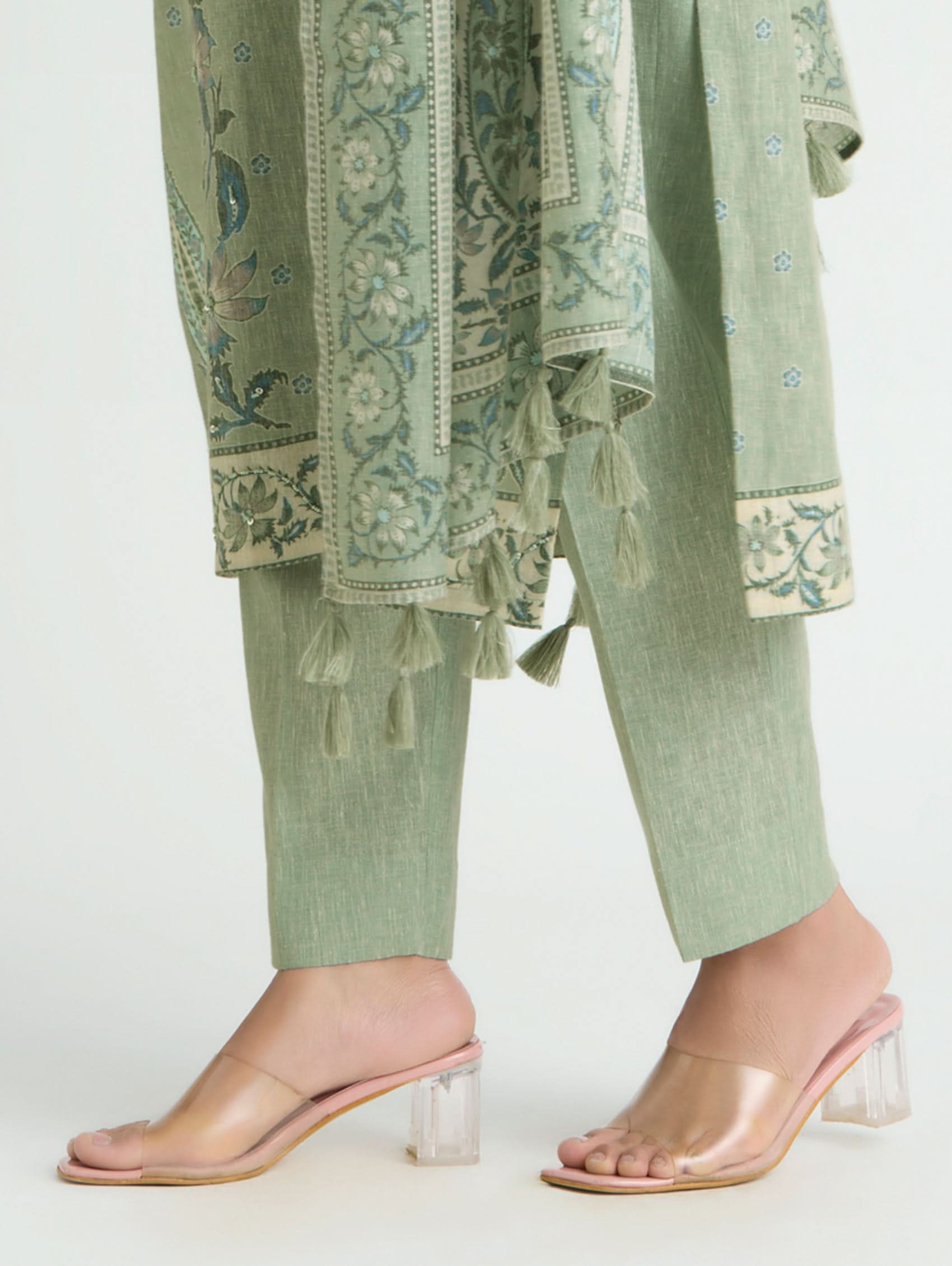 Green embroidered outfit with matching pants and pink sandals on a white background