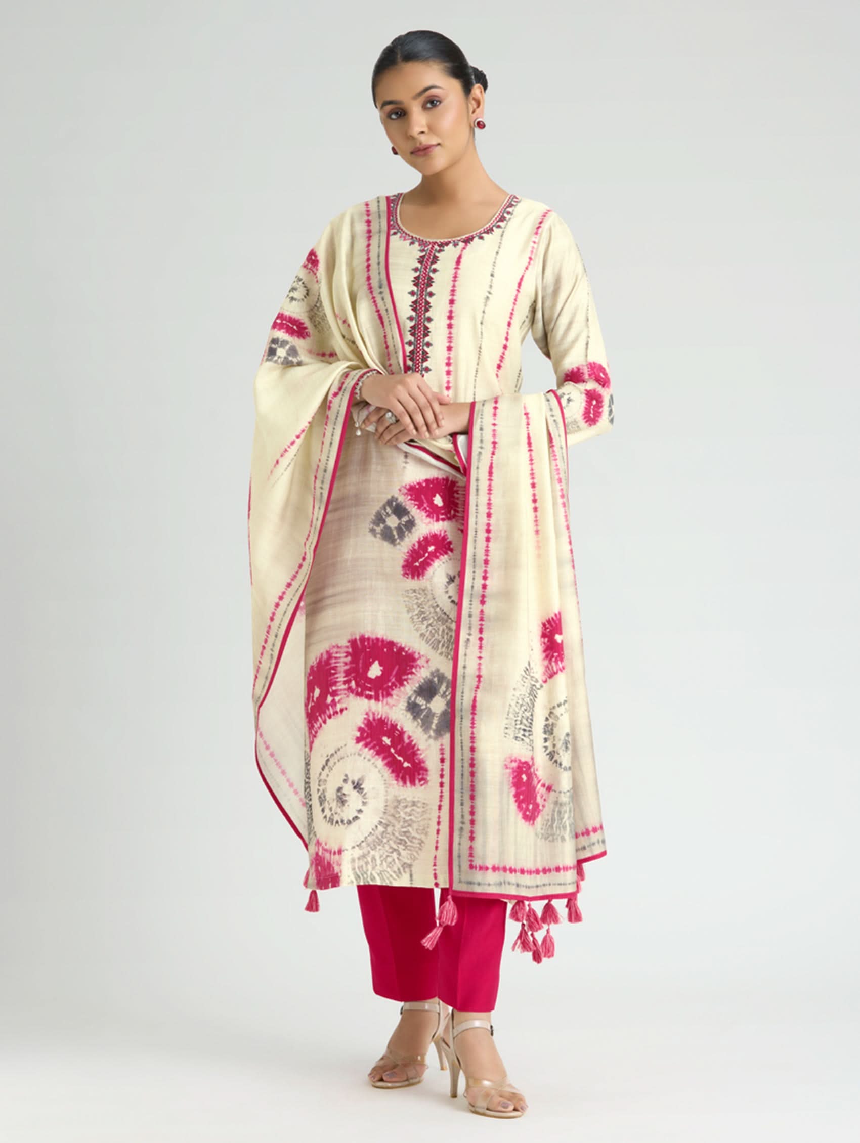 Woman wearing a cream and pink embroidered traditional outfit on a white background
