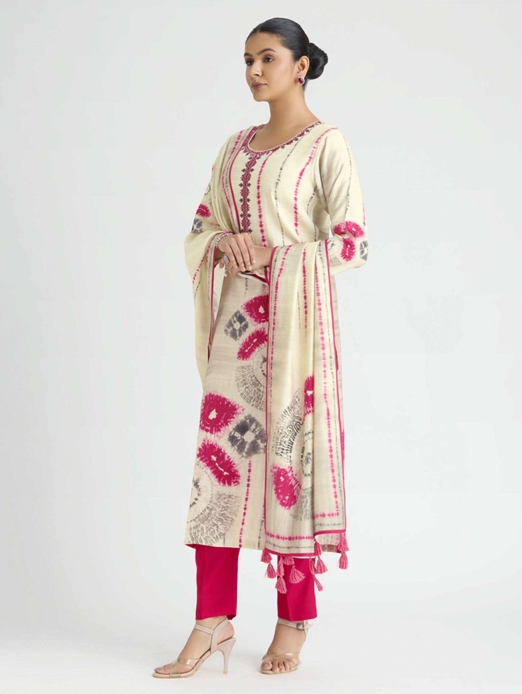 Woman wearing a cream and pink embroidered traditional outfit on a white background