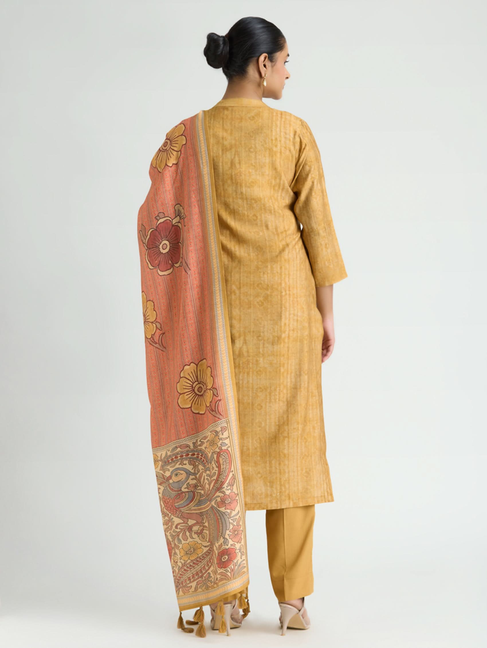 Woman wearing a mustard yellow kurta with a matching dupatta on a white background