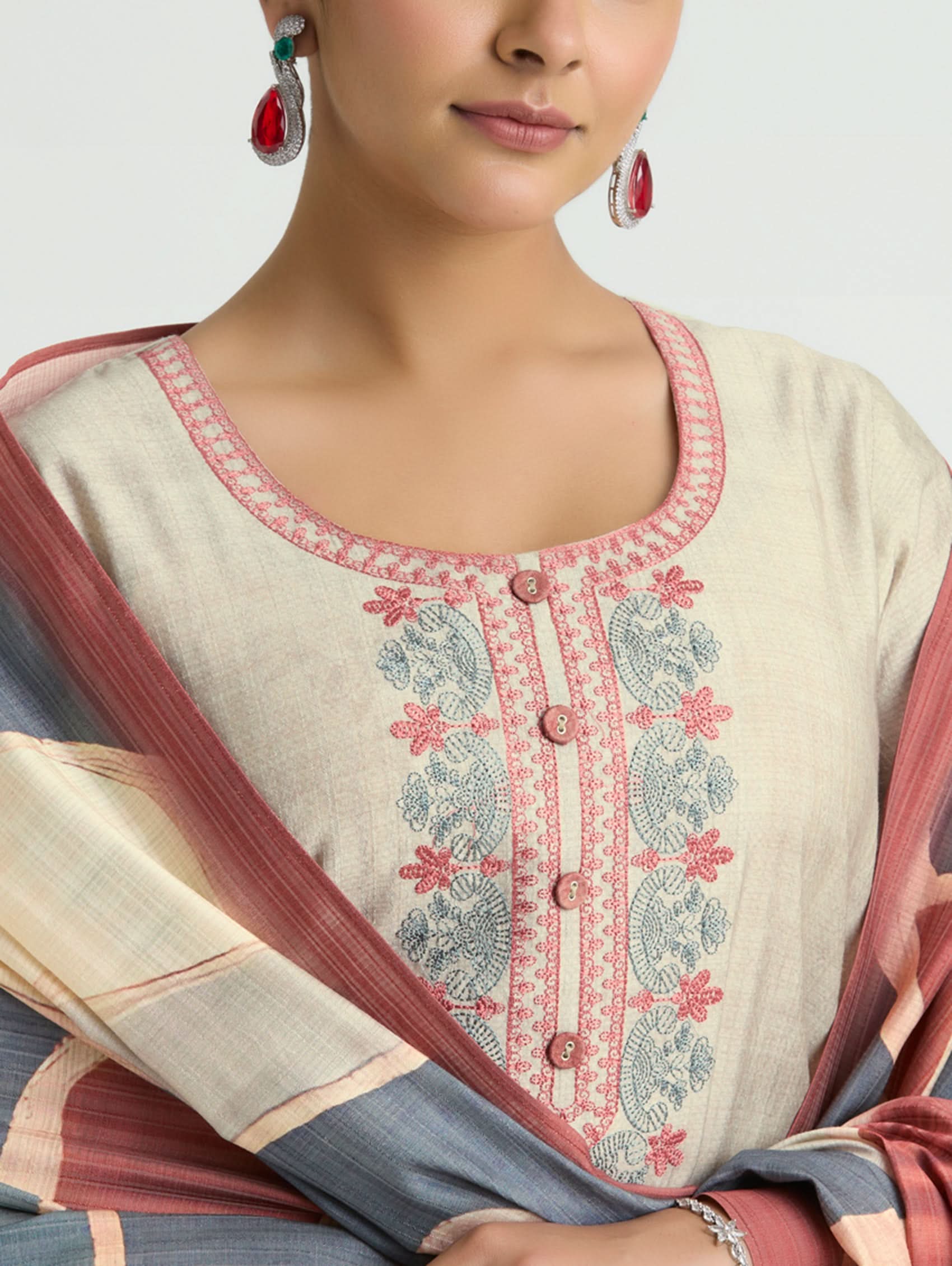 Woman wearing a cream-colored embroidered blouse with a pink border and a matching dupatta.
