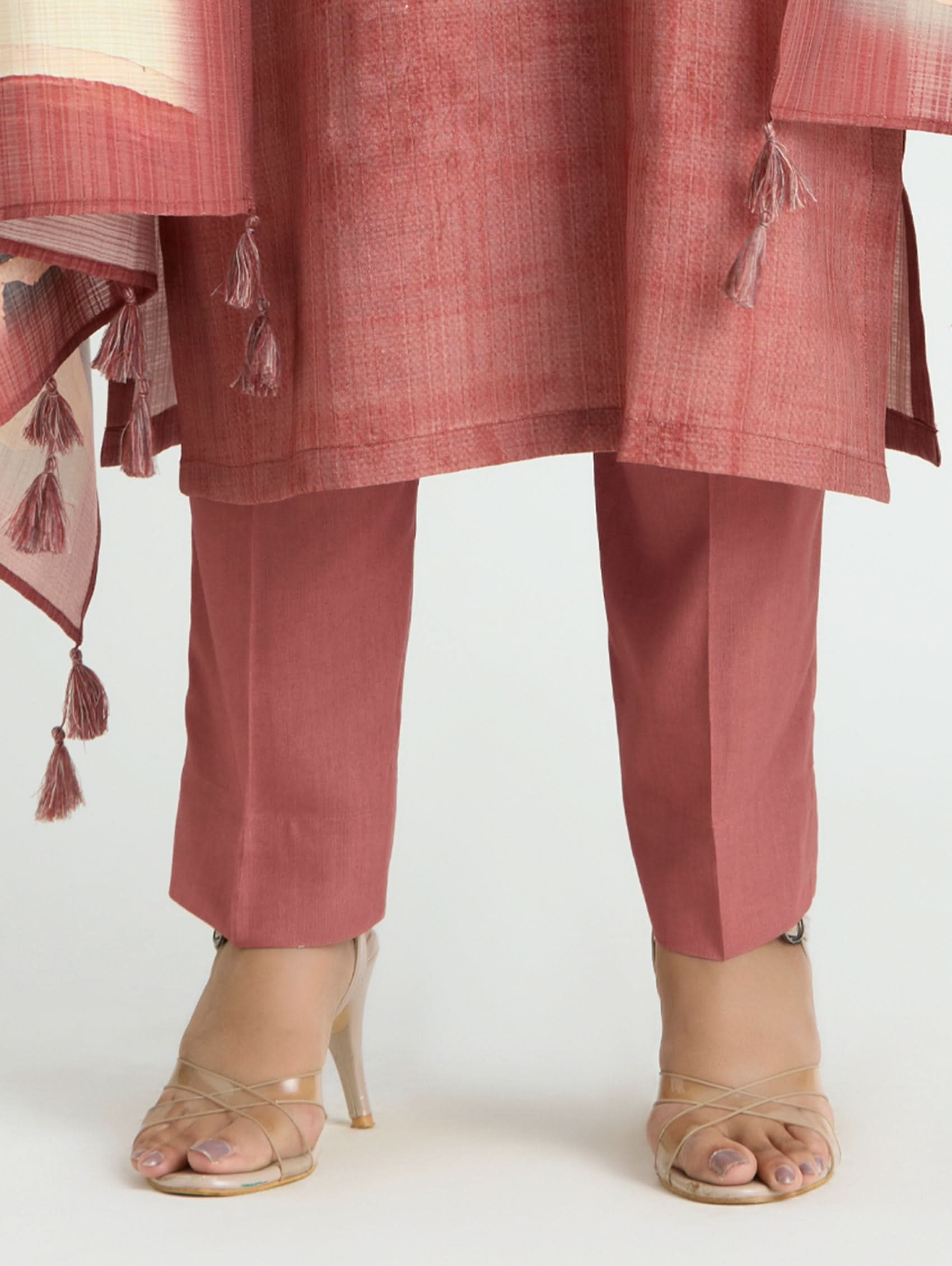 Person wearing a pink traditional outfit with a scarf and high-heeled sandals on a white background