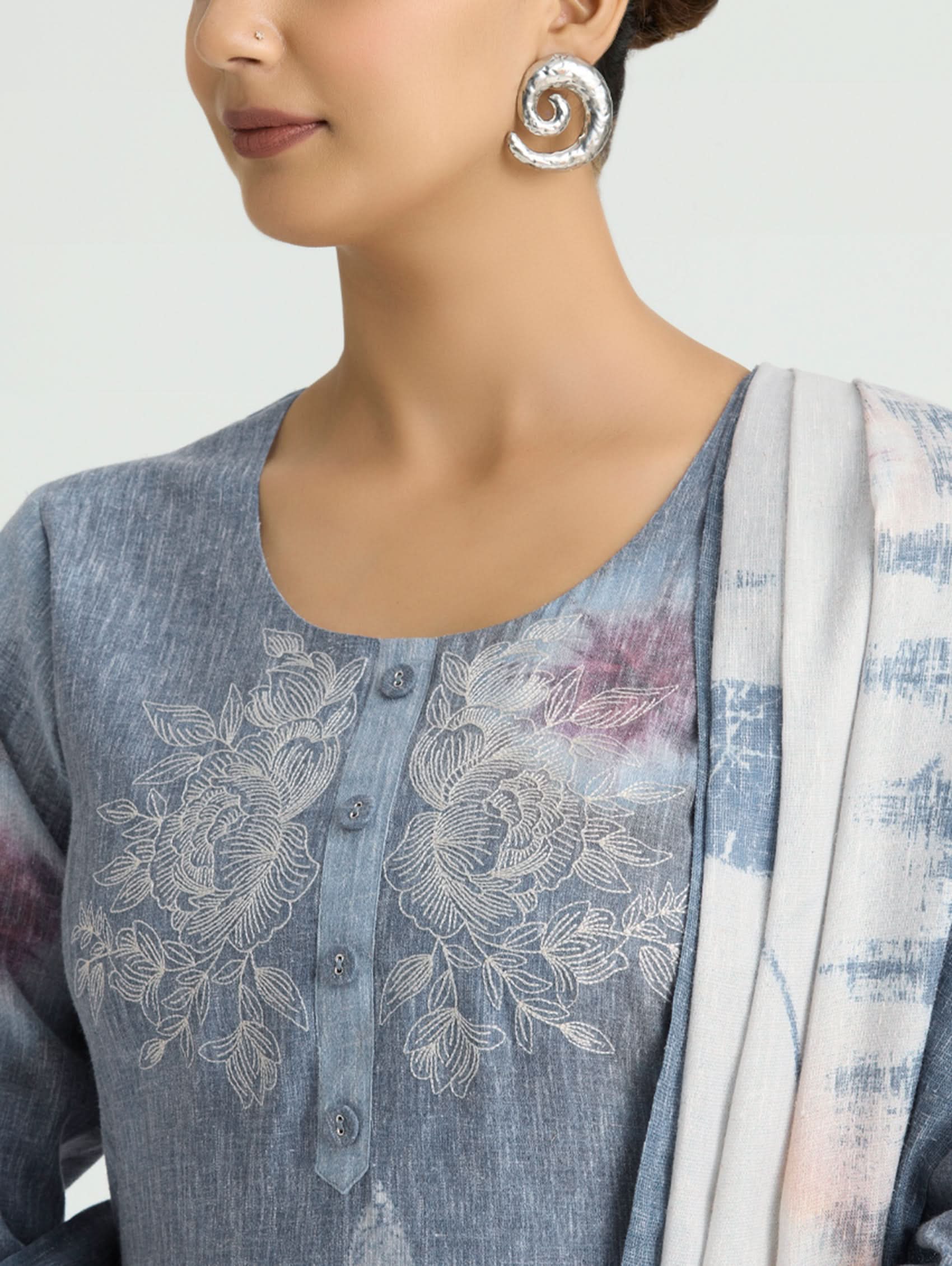Woman wearing a blue embroidered outfit with a white background