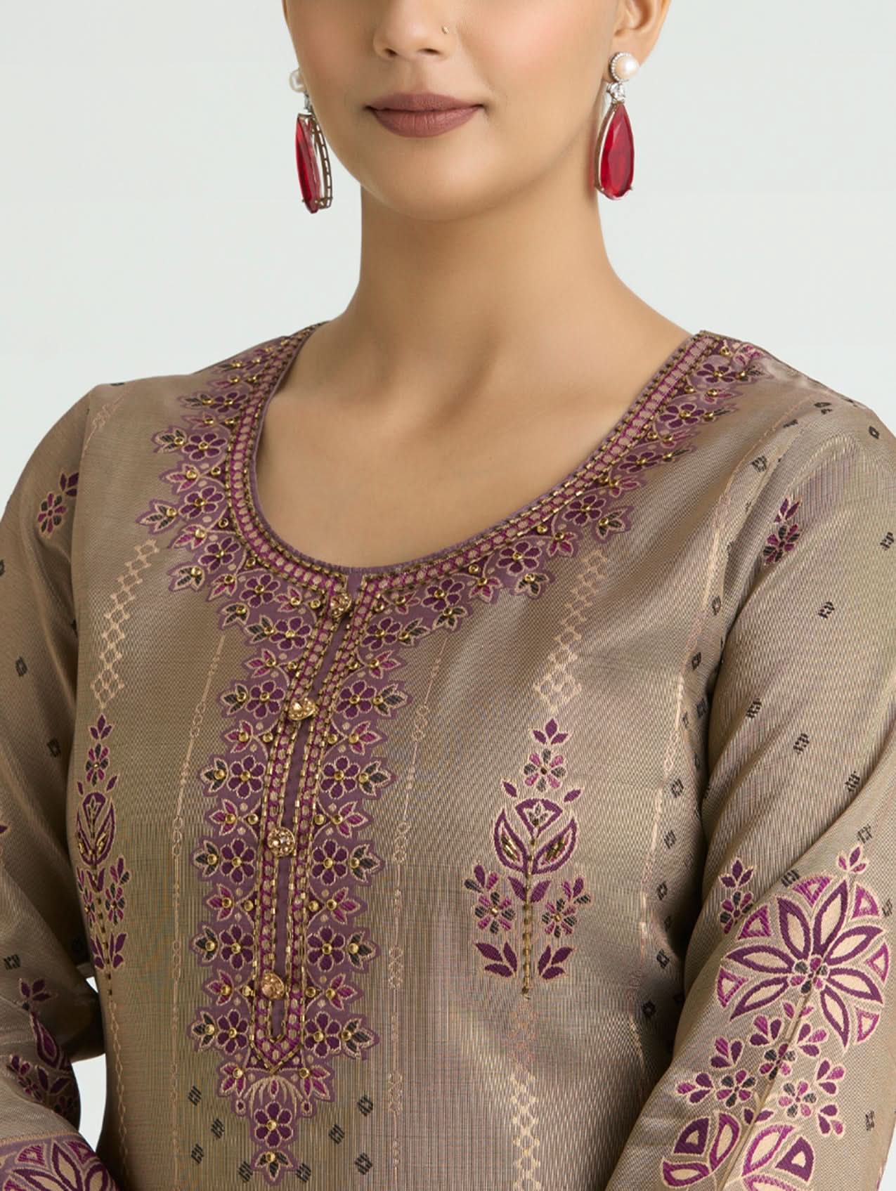 Close-up of a brown embroidered garment with intricate patterns on a plain background