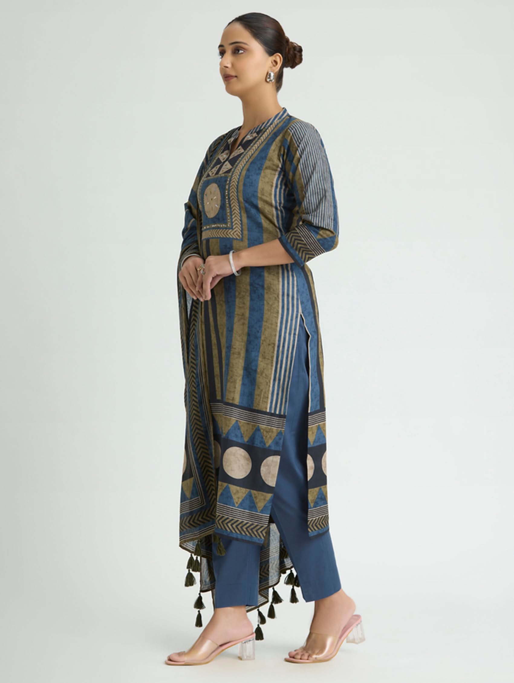 Woman wearing a blue and black patterned outfit with tassels on a white background