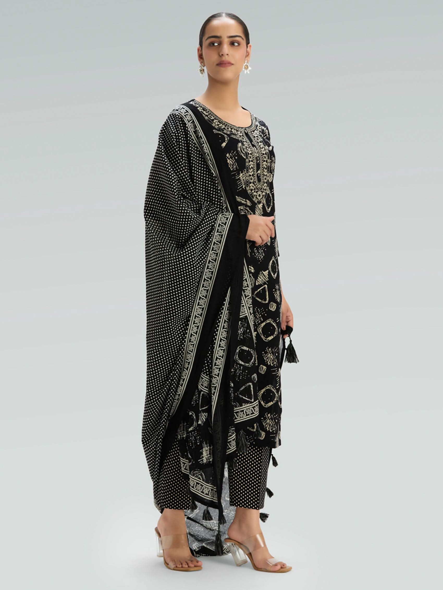 Woman wearing a Black outfit with a patterned Dupatta on a light gray background