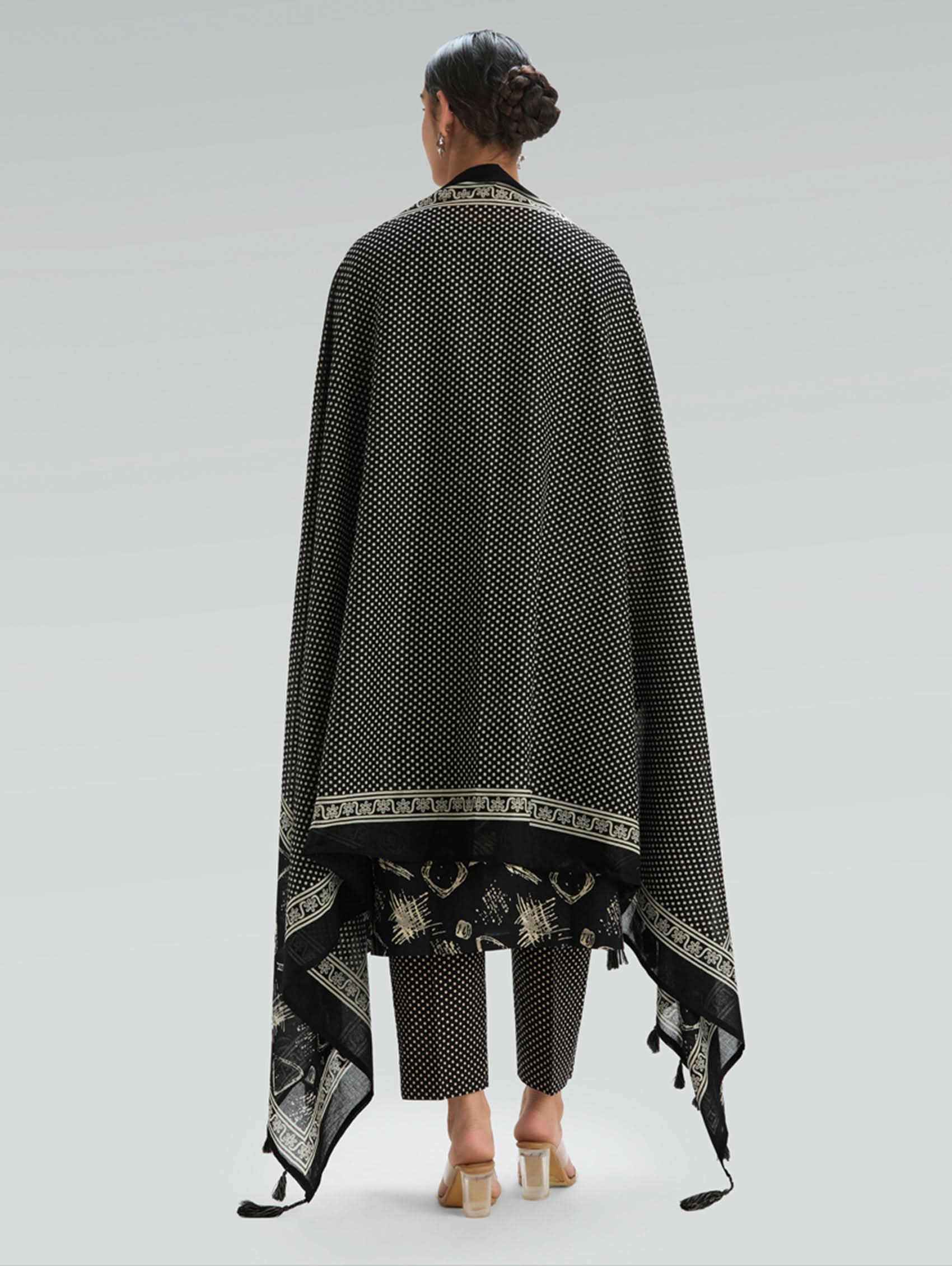 Woman wearing a Black outfit with a patterned Dupatta on a light gray background