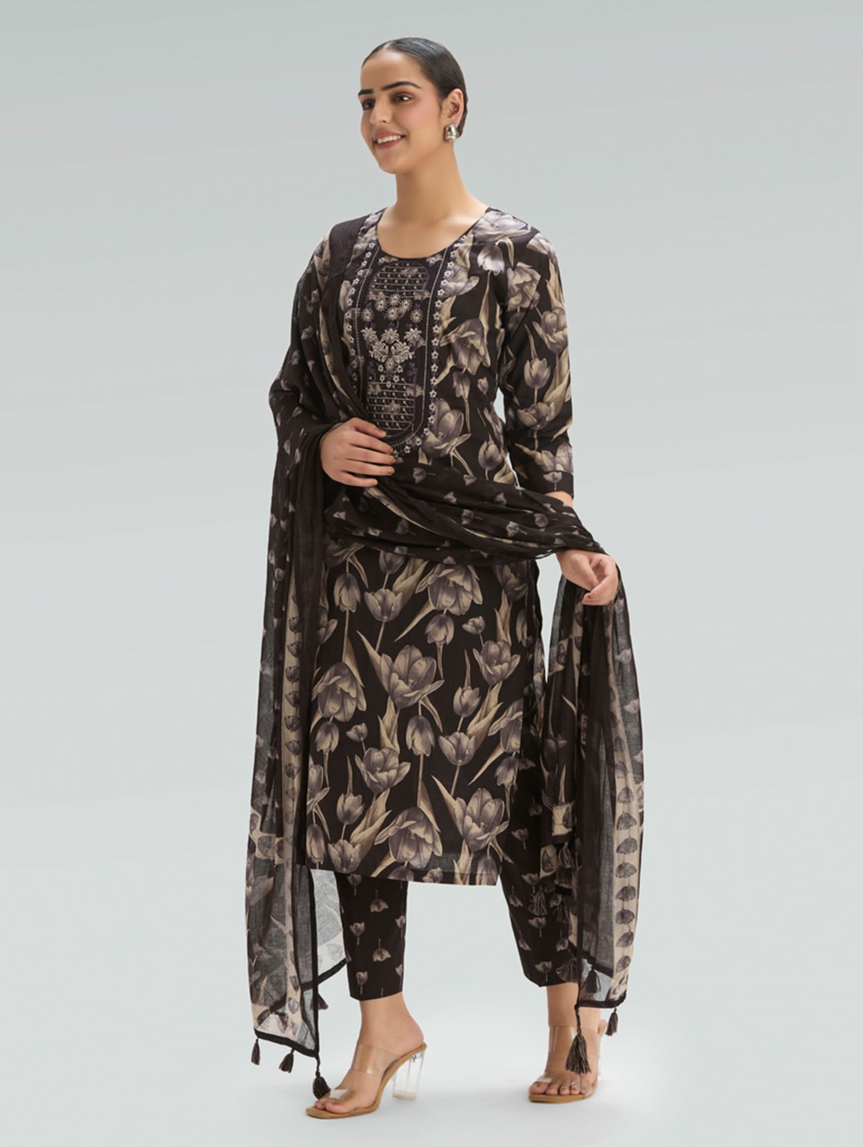 Woman wearing a black floral dress with sheer sleeves on a light gray background