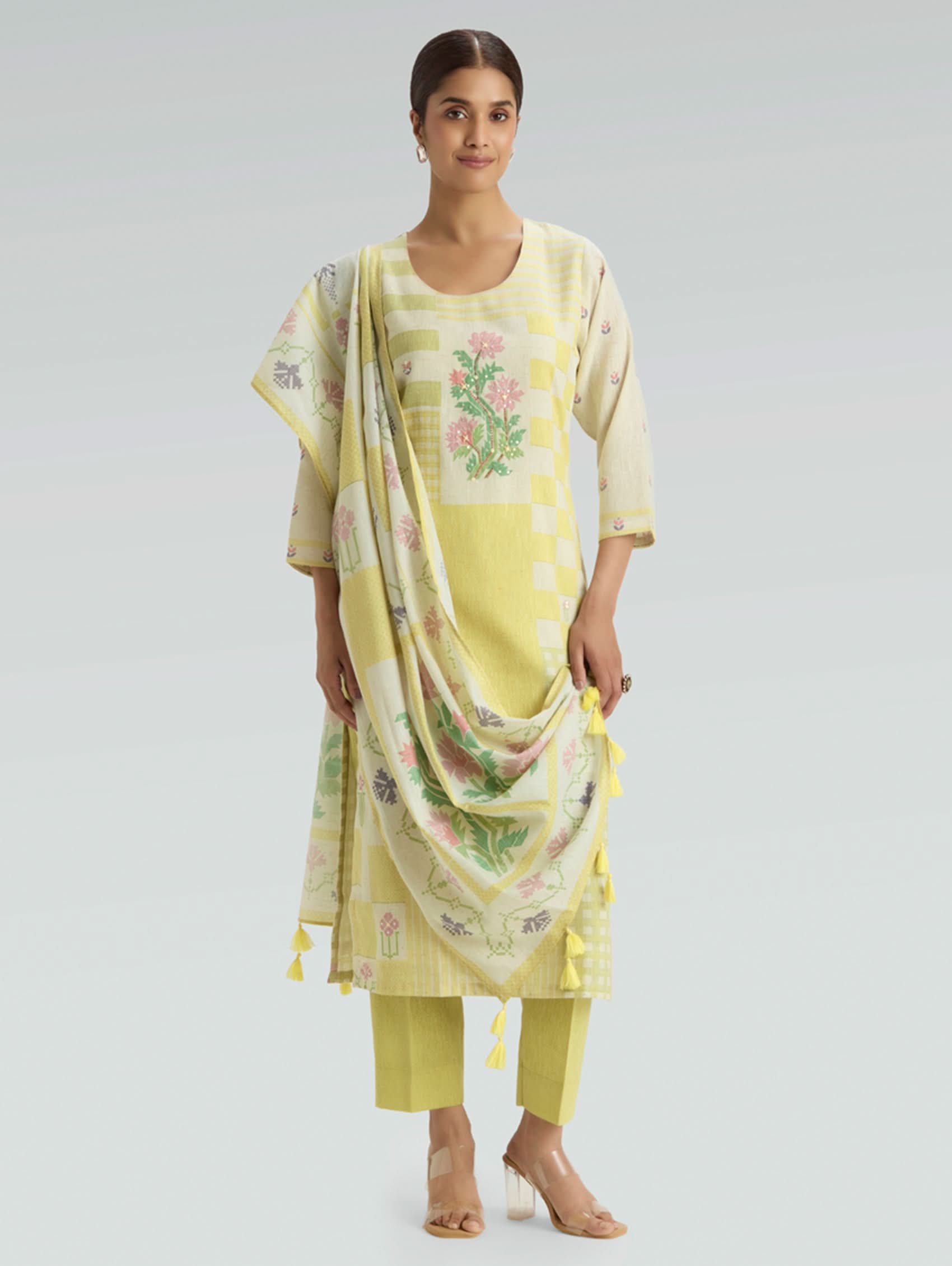 Woman wearing a yellow traditional outfit with a matching dupatta on a light gray background