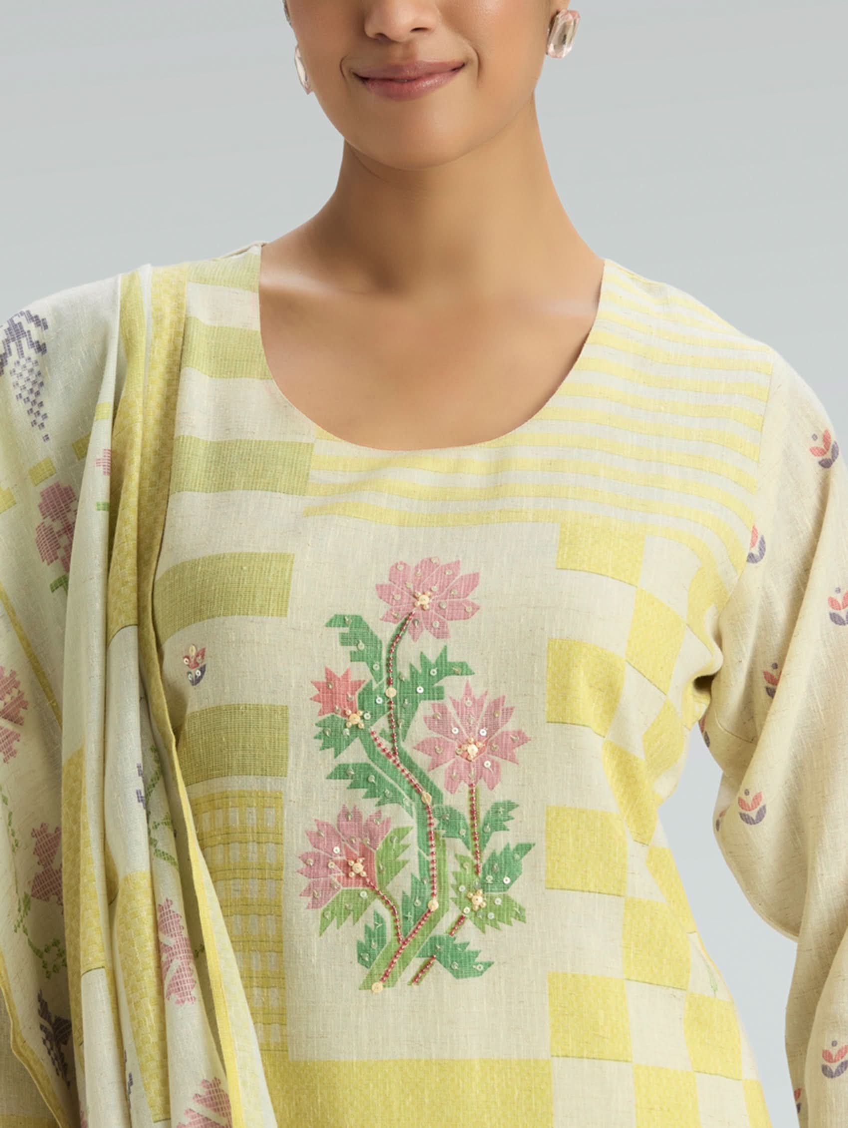 Woman wearing a traditional outfit with floral embroidery on a plain background
